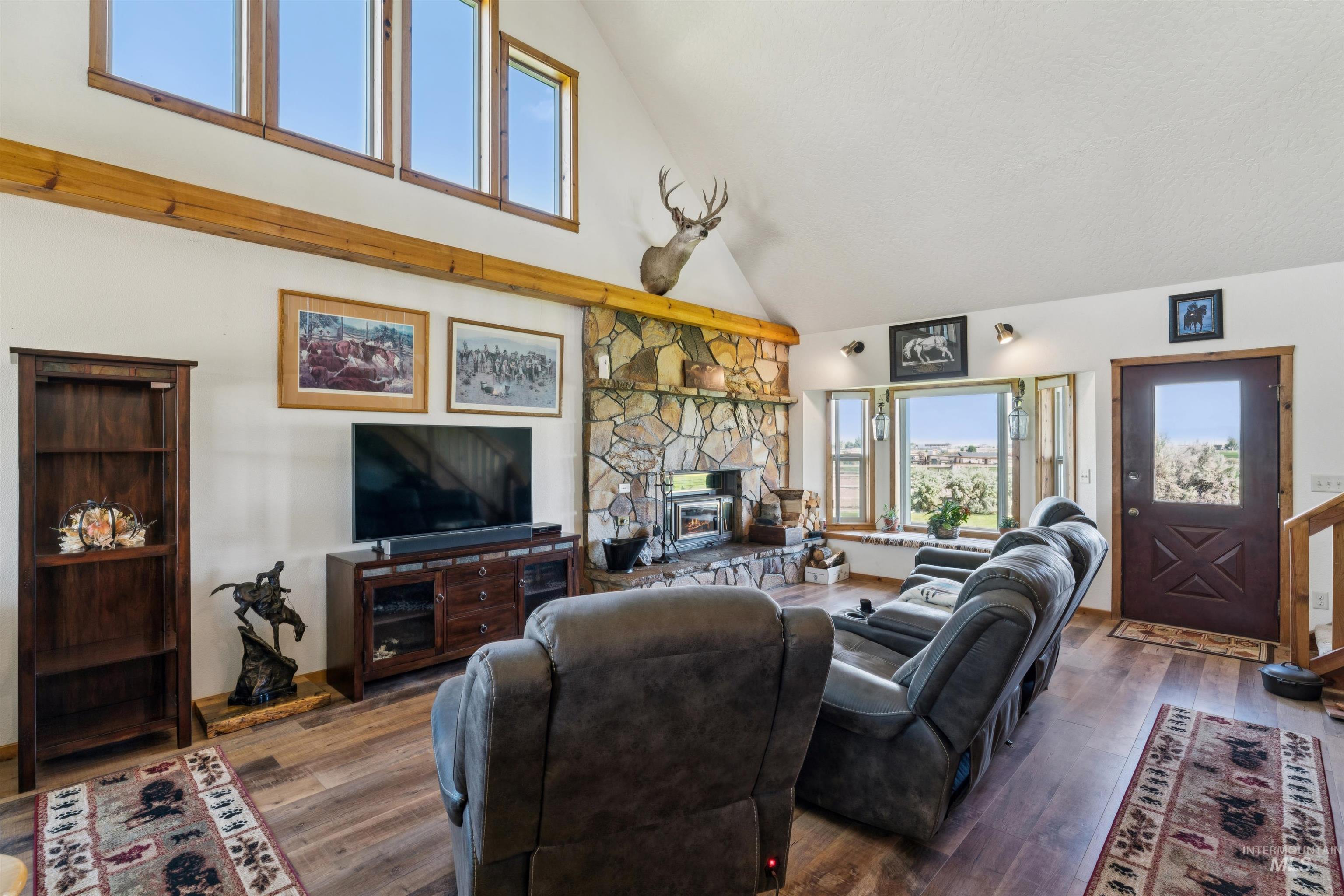 Living room with a vaulted ceiling, stone fireplace, and dark leather reclining sofas.