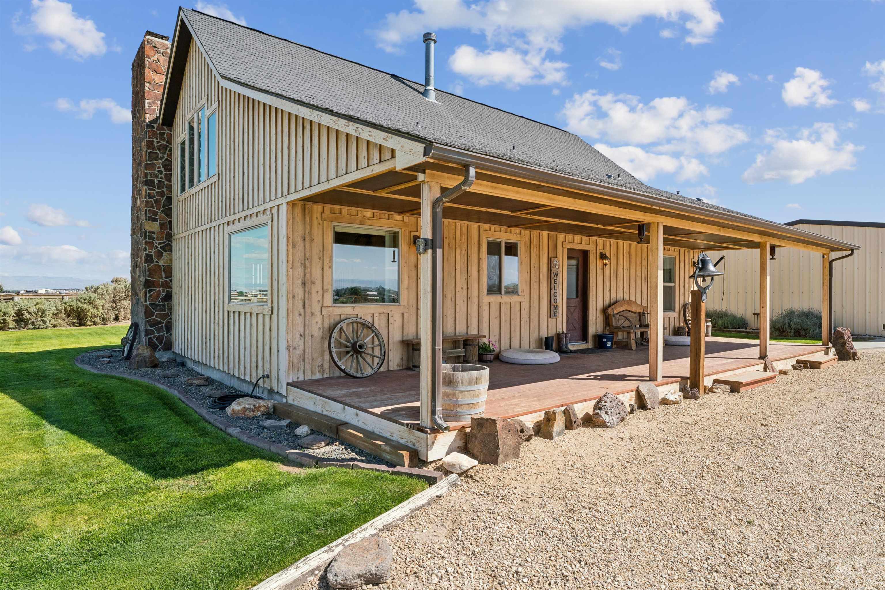 Rustic wood-sided home with a stone chimney and a long covered porch.