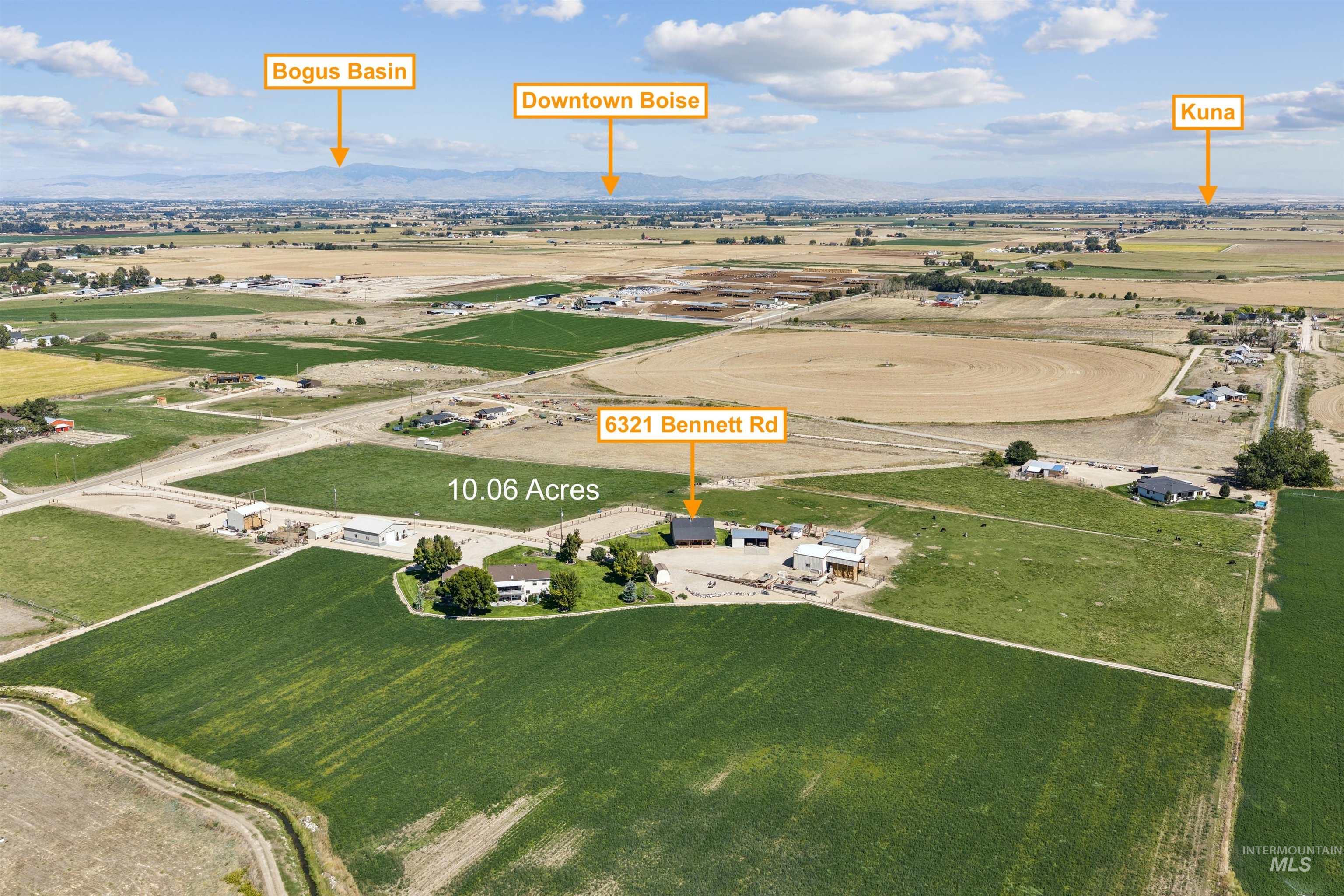 Aerial view of 10.06-acre property with a home and outbuildings amid farmland, with distant mountains.