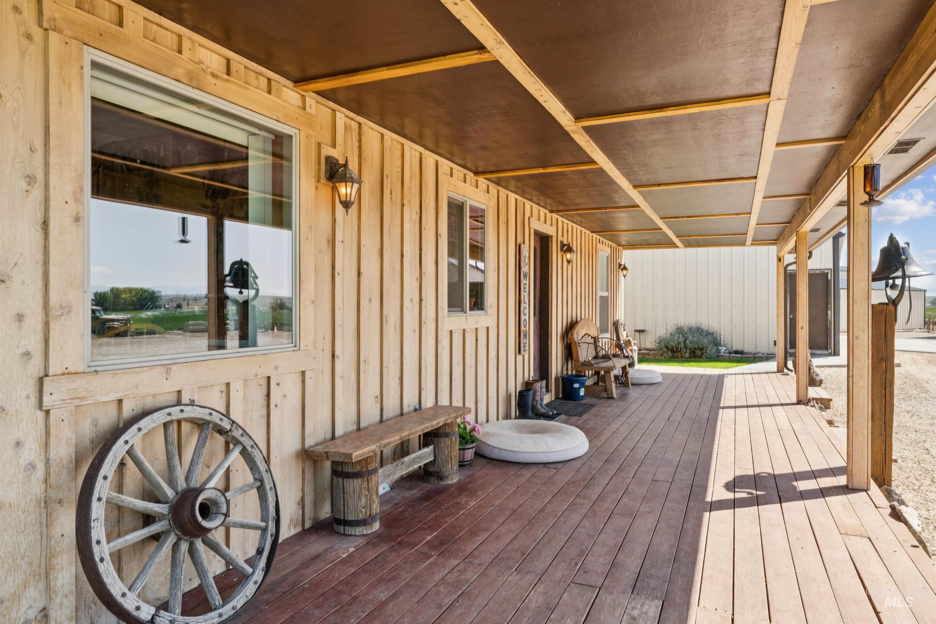 Covered wooden porch with rustic benches, a wagon wheel, and lanterns.
