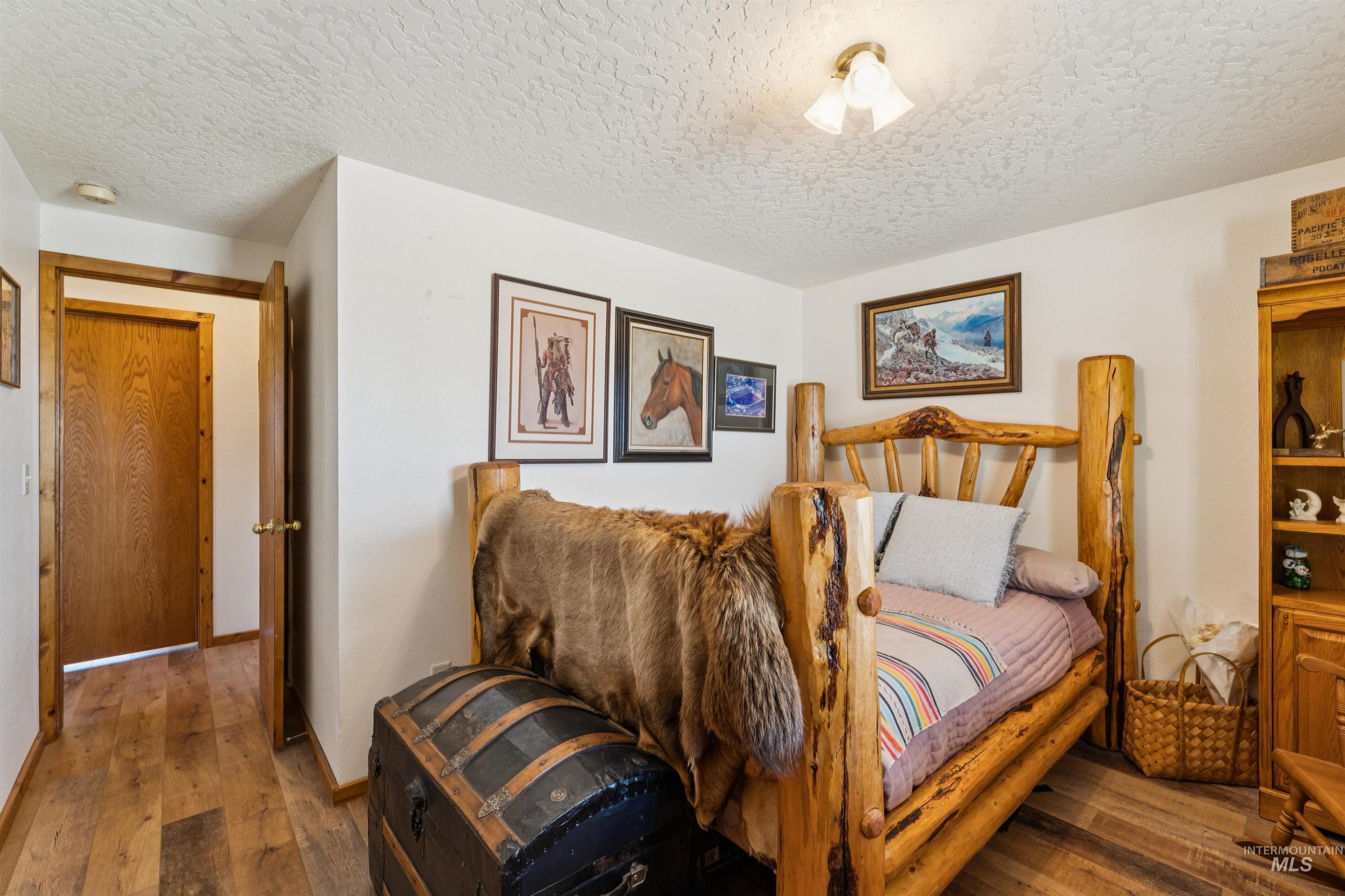 Furnished bedroom with a rustic log bed, fur throw, and framed Western artwork.