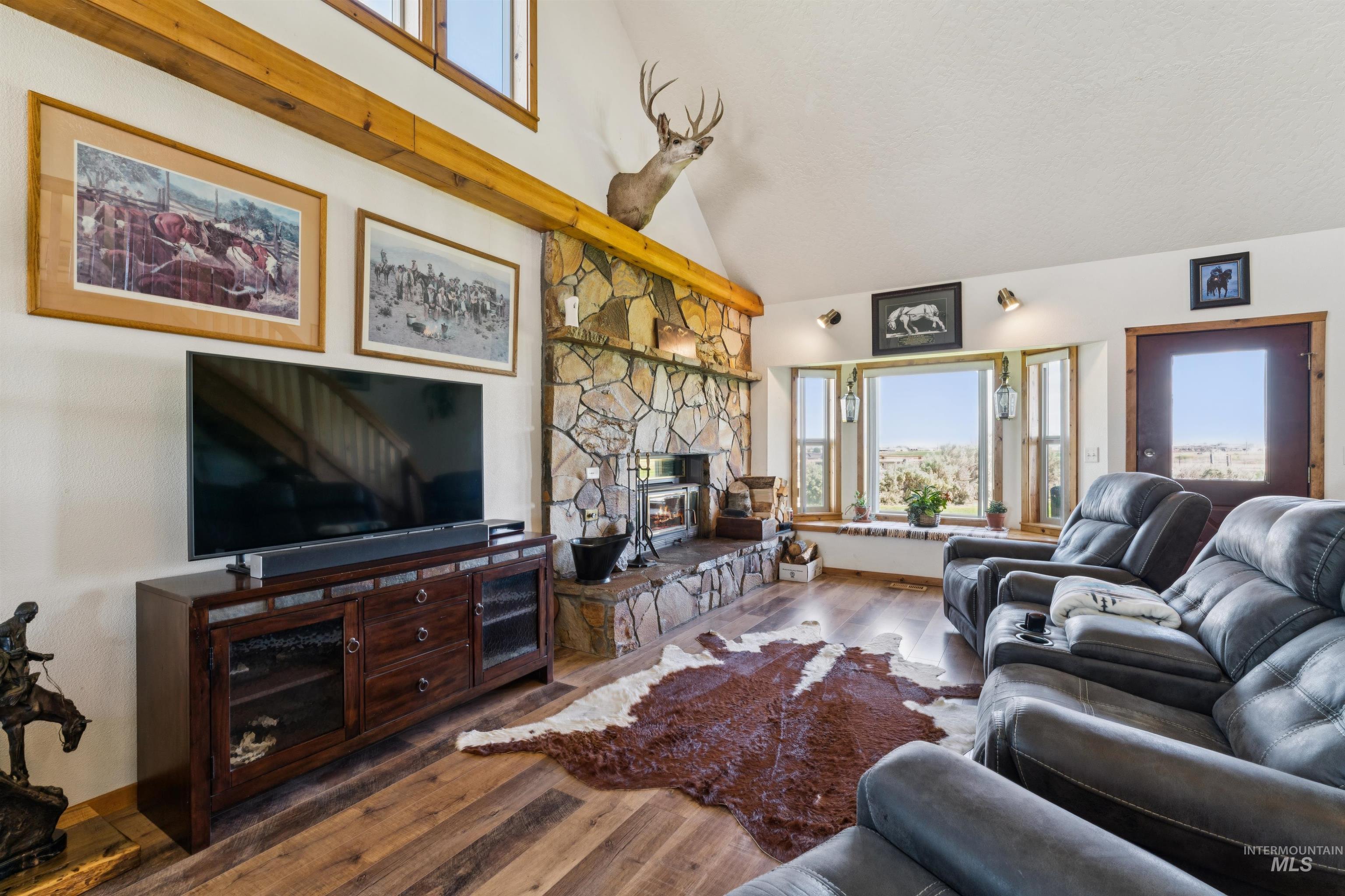 Living room with a stone fireplace, exposed timber beams, and a leather sectional.