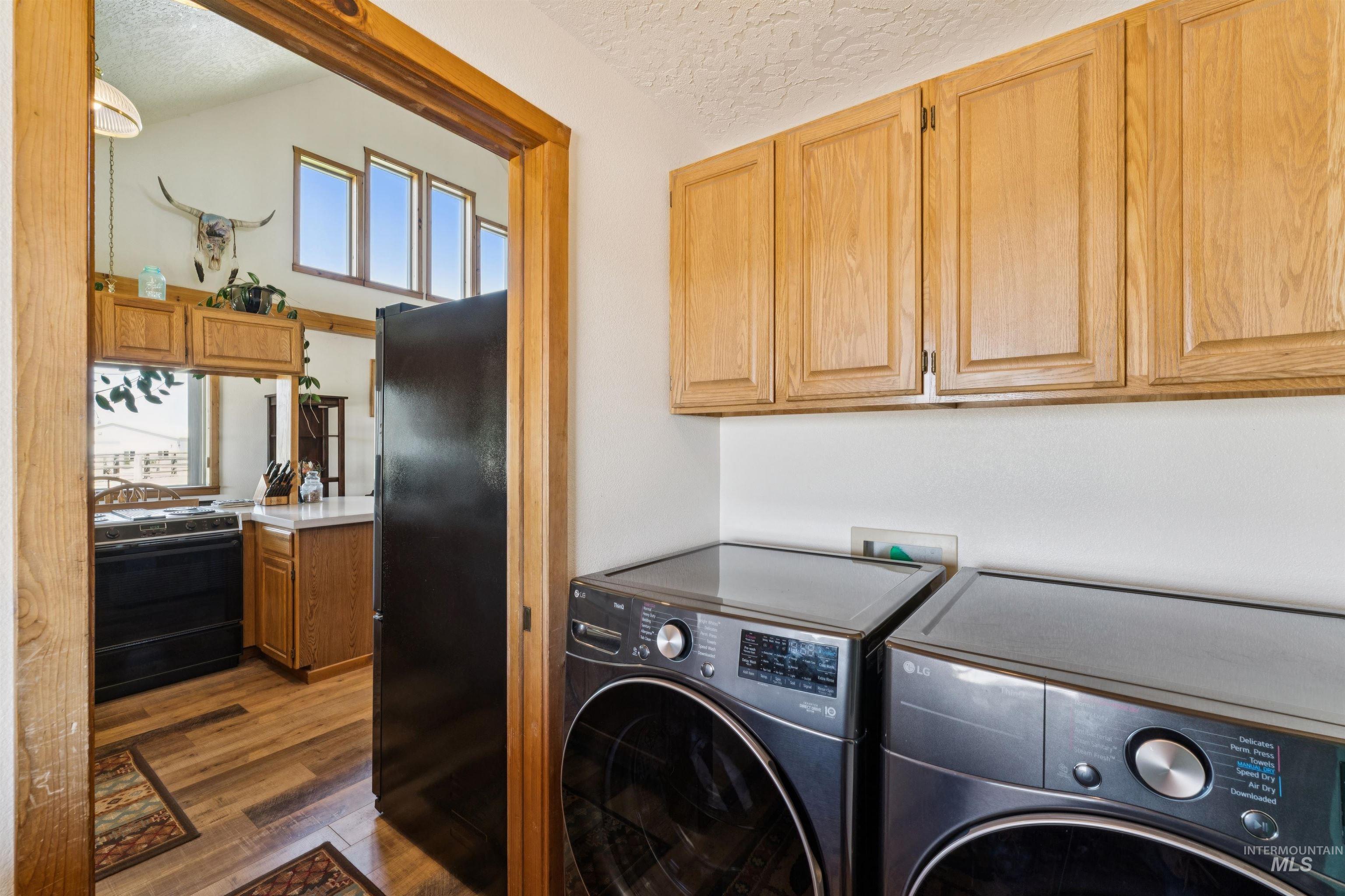 Laundry room with LG washer and dryer beneath oak cabinets, opening into a kitchen.