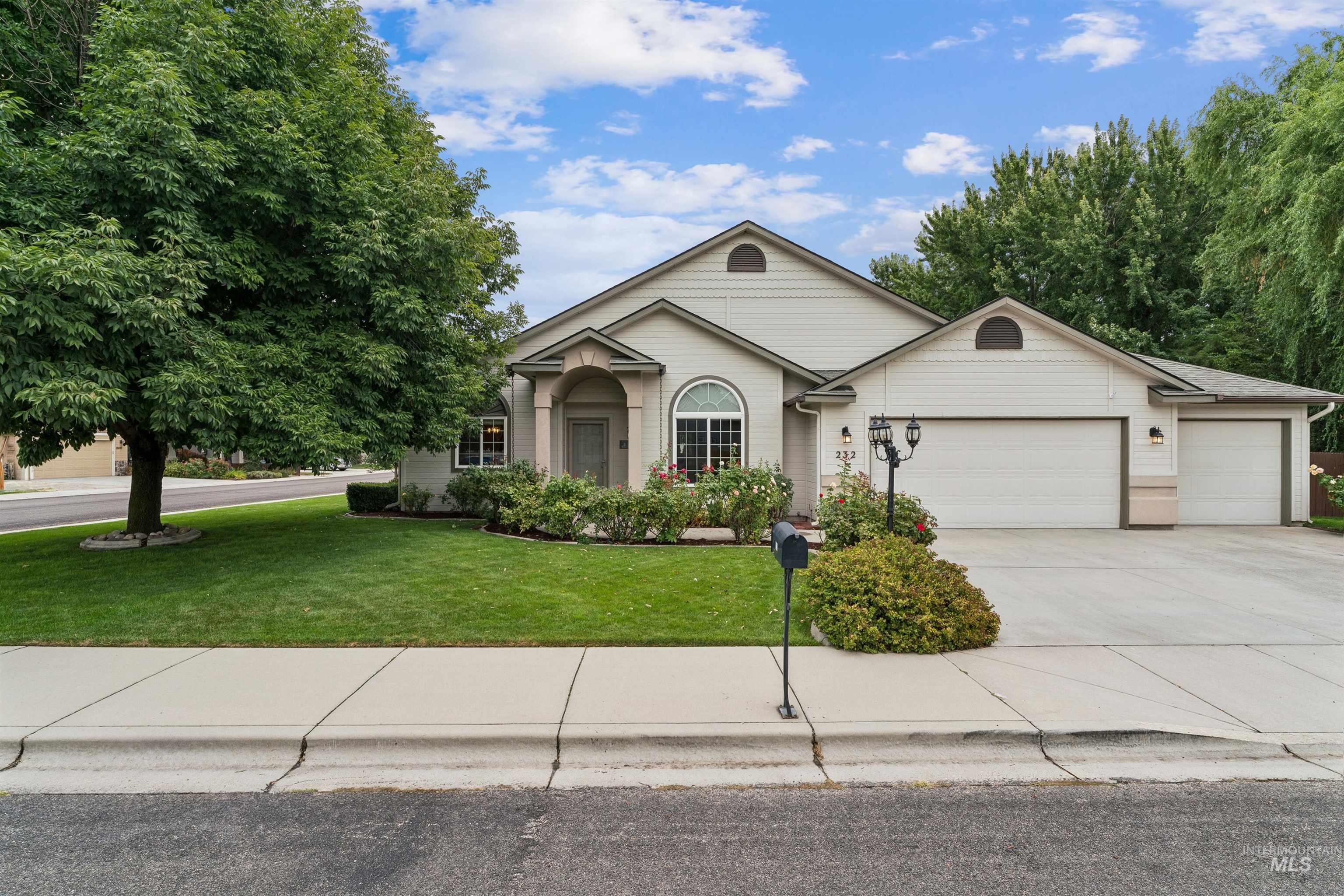 Home at 232 Taurus Way with an arched entry, attached garage, landscaped lawn, and mature trees.