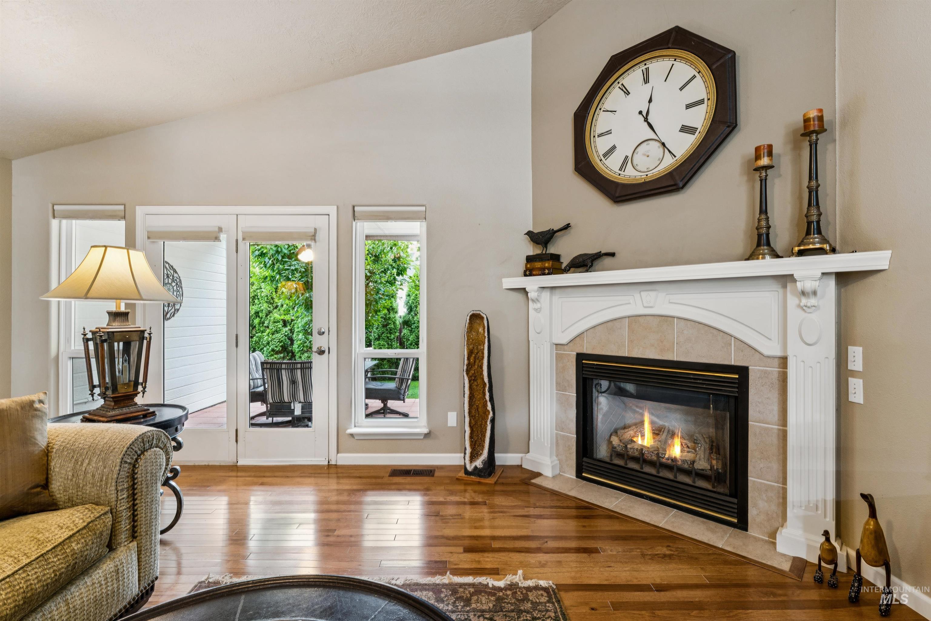 Living room with a tiled fireplace, hardwood floors, and glass doors opening to a patio.