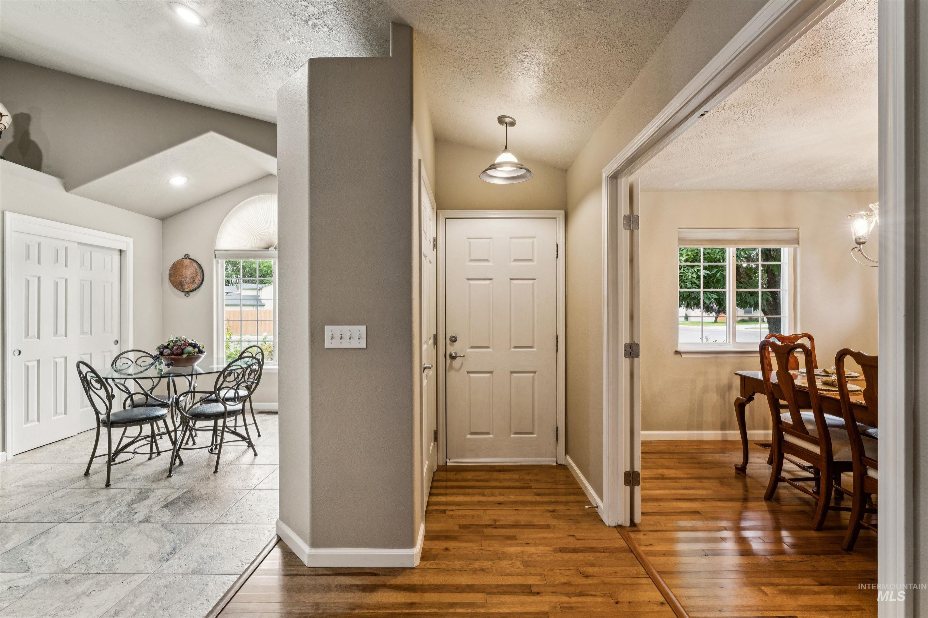 Entryway with a white front door, warm wood floors, and adjoining dining room and breakfast nook.
