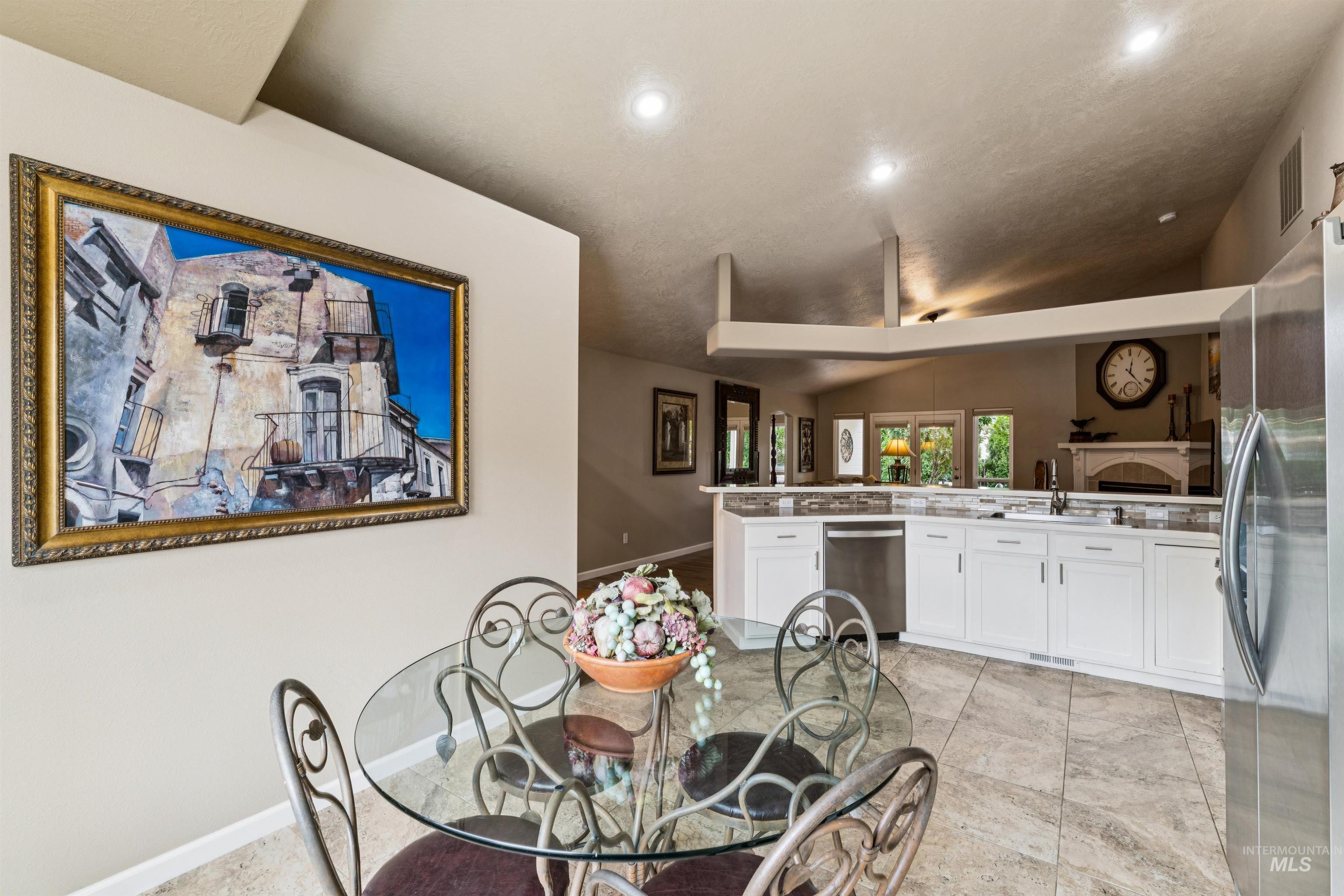 Open kitchen and dining area with white cabinets, stainless appliances, and a glass dining table.