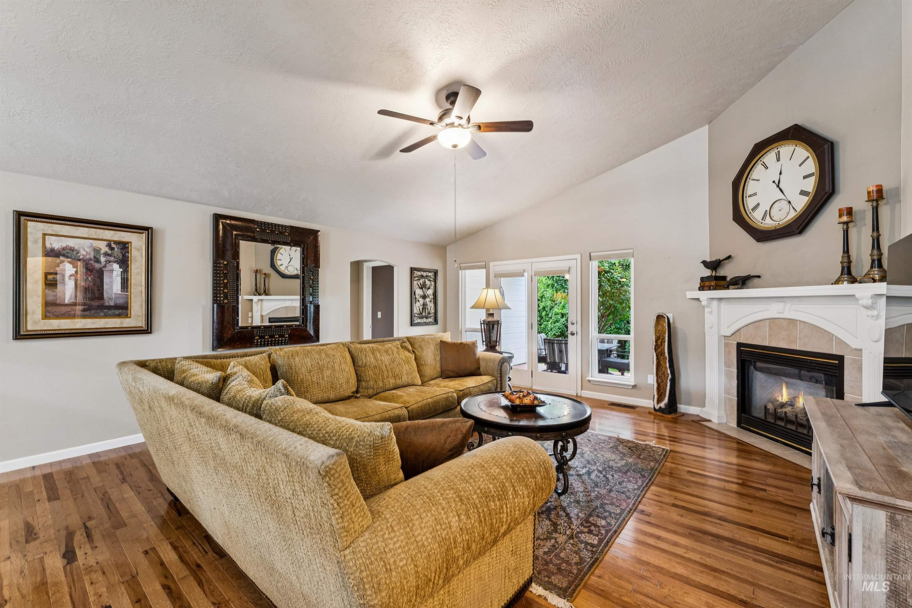 Living room with a golden sectional sofa, hardwood floors, and a fireplace beside glass patio doors.