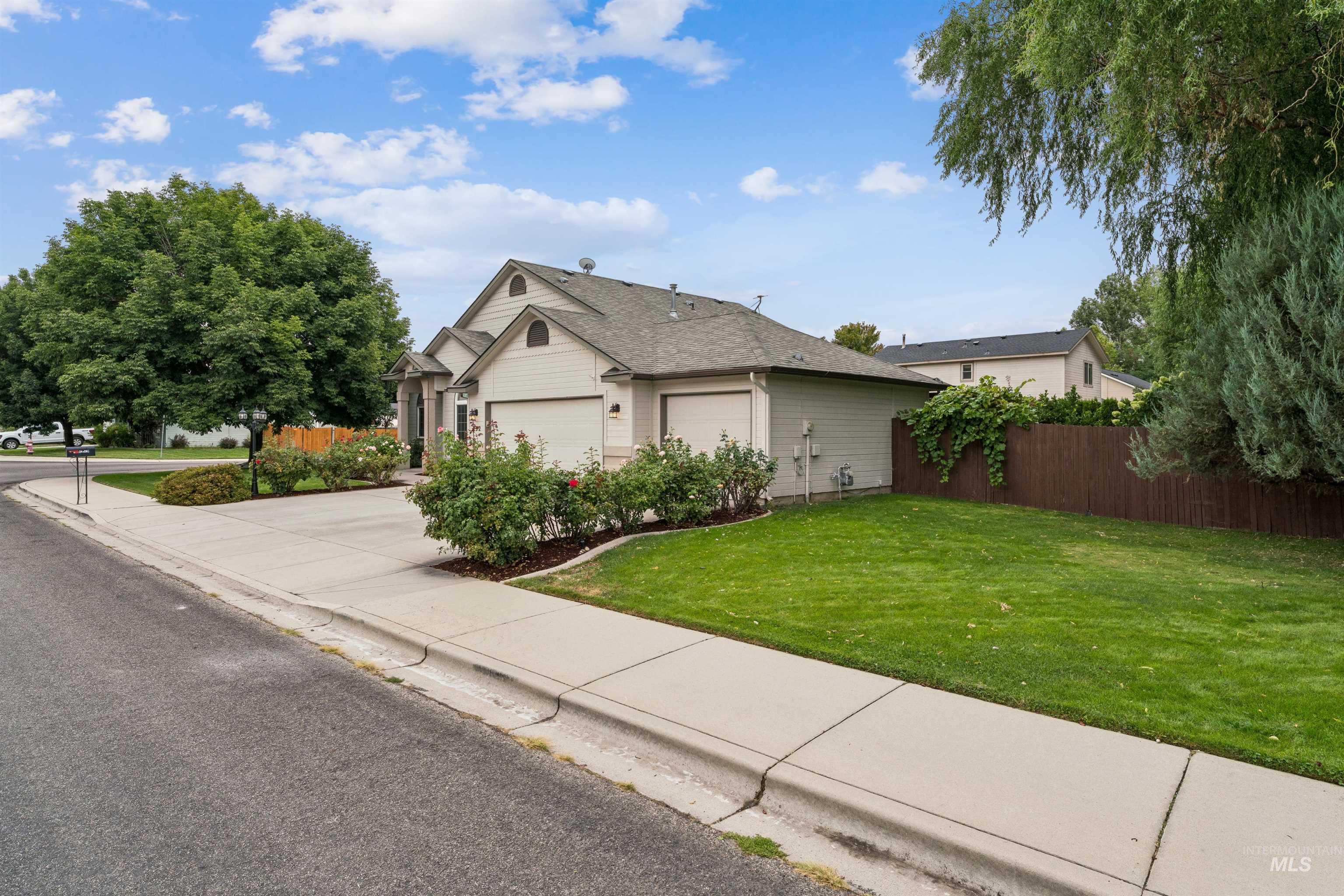Beige home with a two-car garage, rose bushes, and a green front lawn.