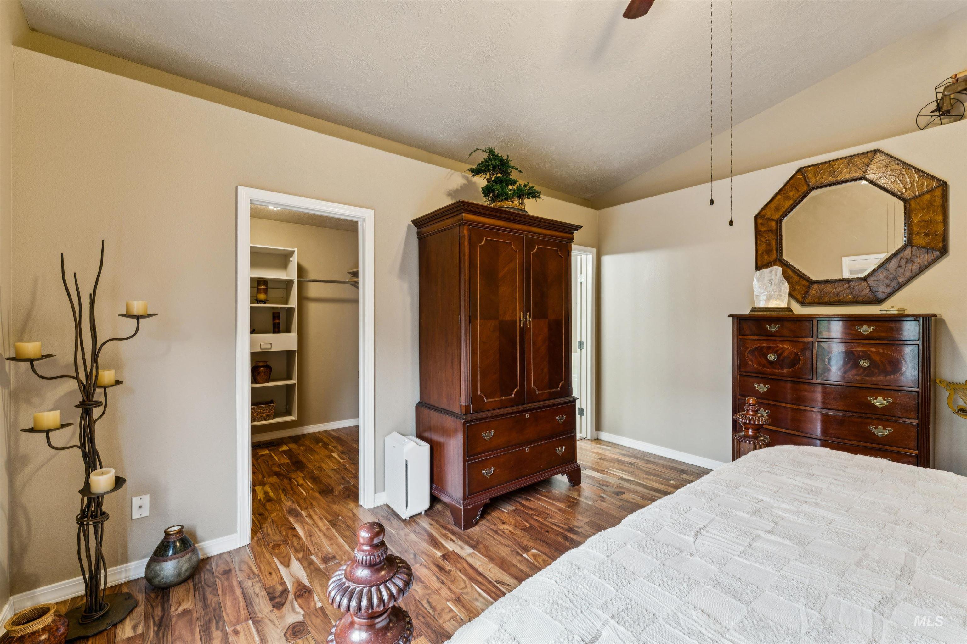 Bedroom with dark wood dressers, an octagonal mirror, and an open walk-in closet.