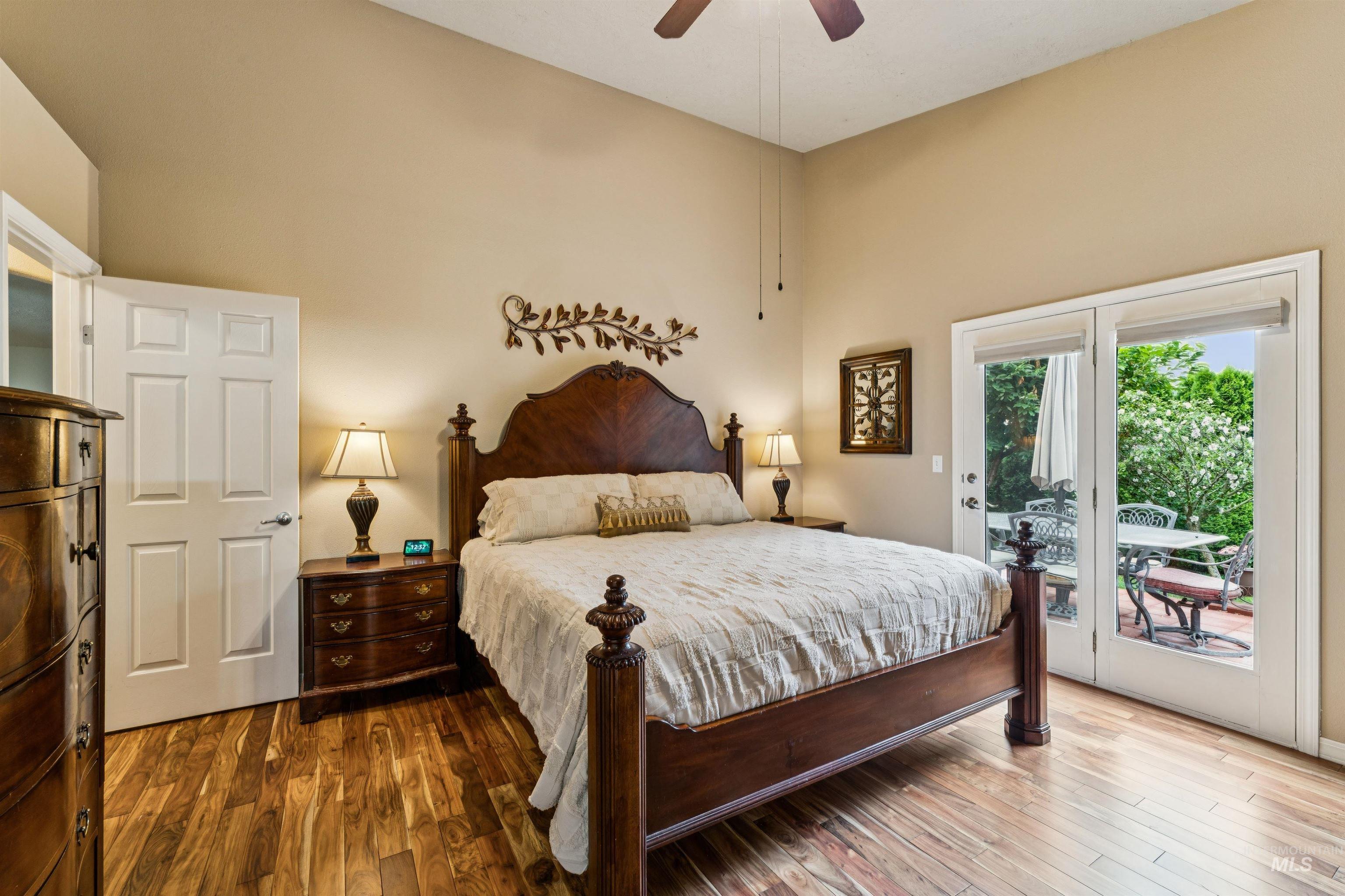 Bedroom with a dark wood four-poster bed and patio doors opening onto a garden.