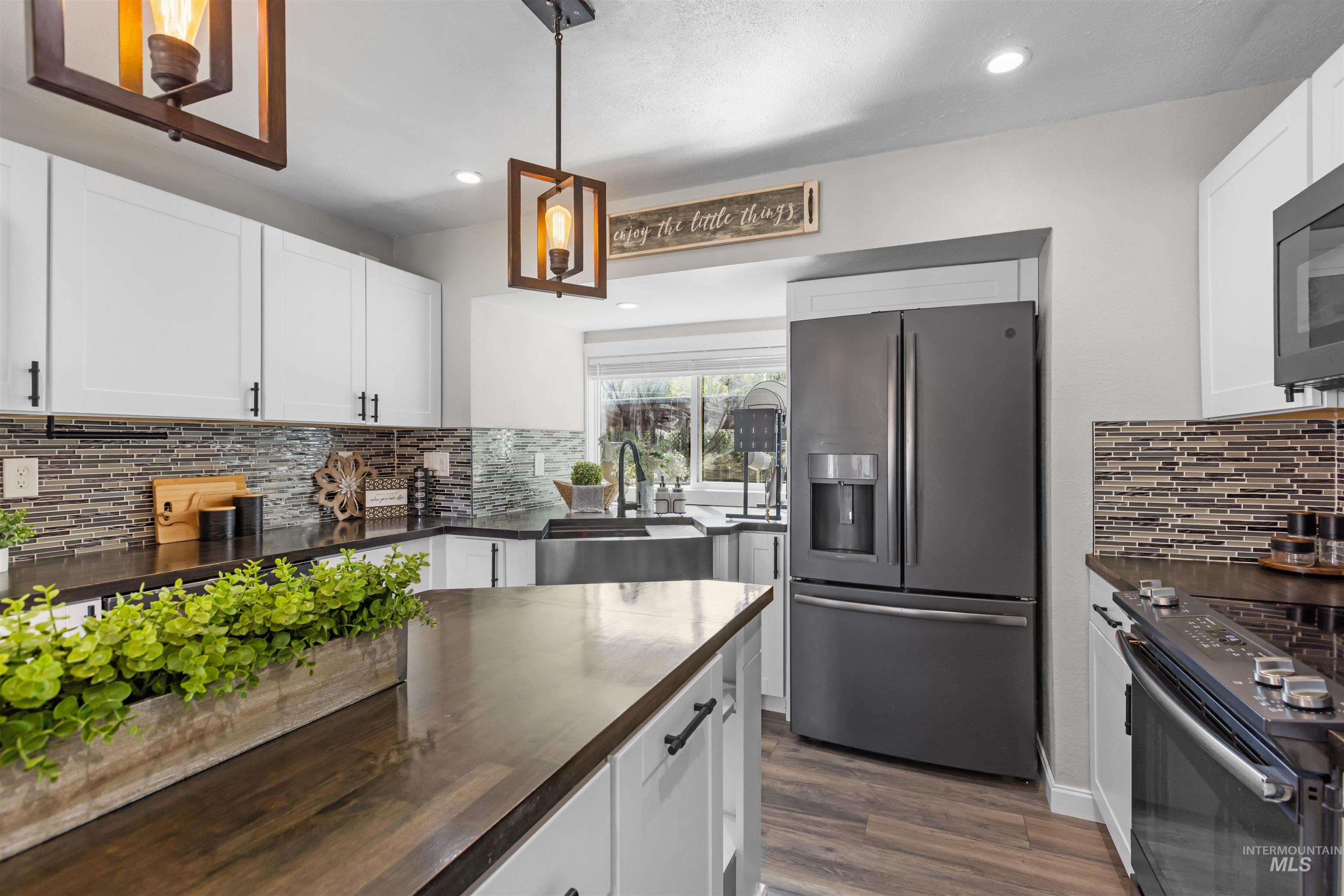 Kitchen with white cabinets, dark countertops, stainless appliances, and a farmhouse sink.