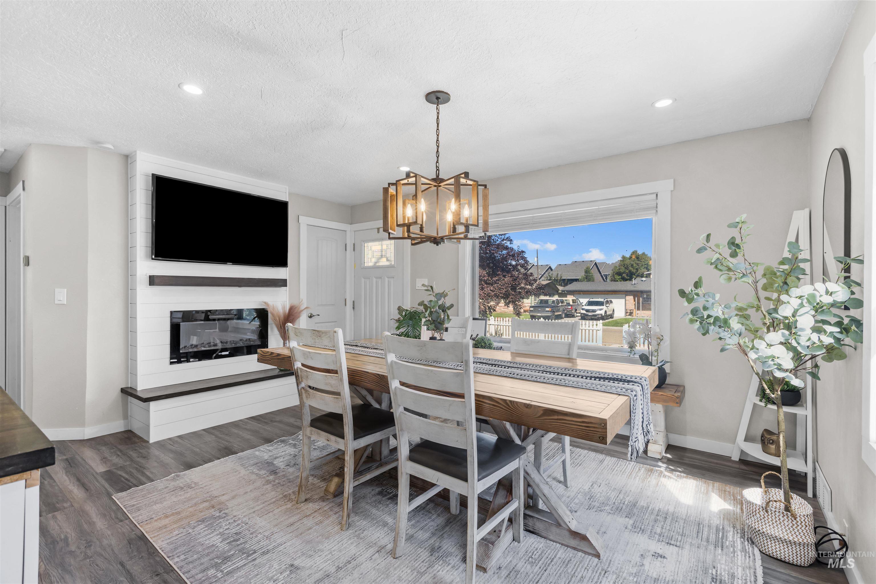 Staged dining area with a rustic wood table, geometric pendant light, and built-in fireplace.