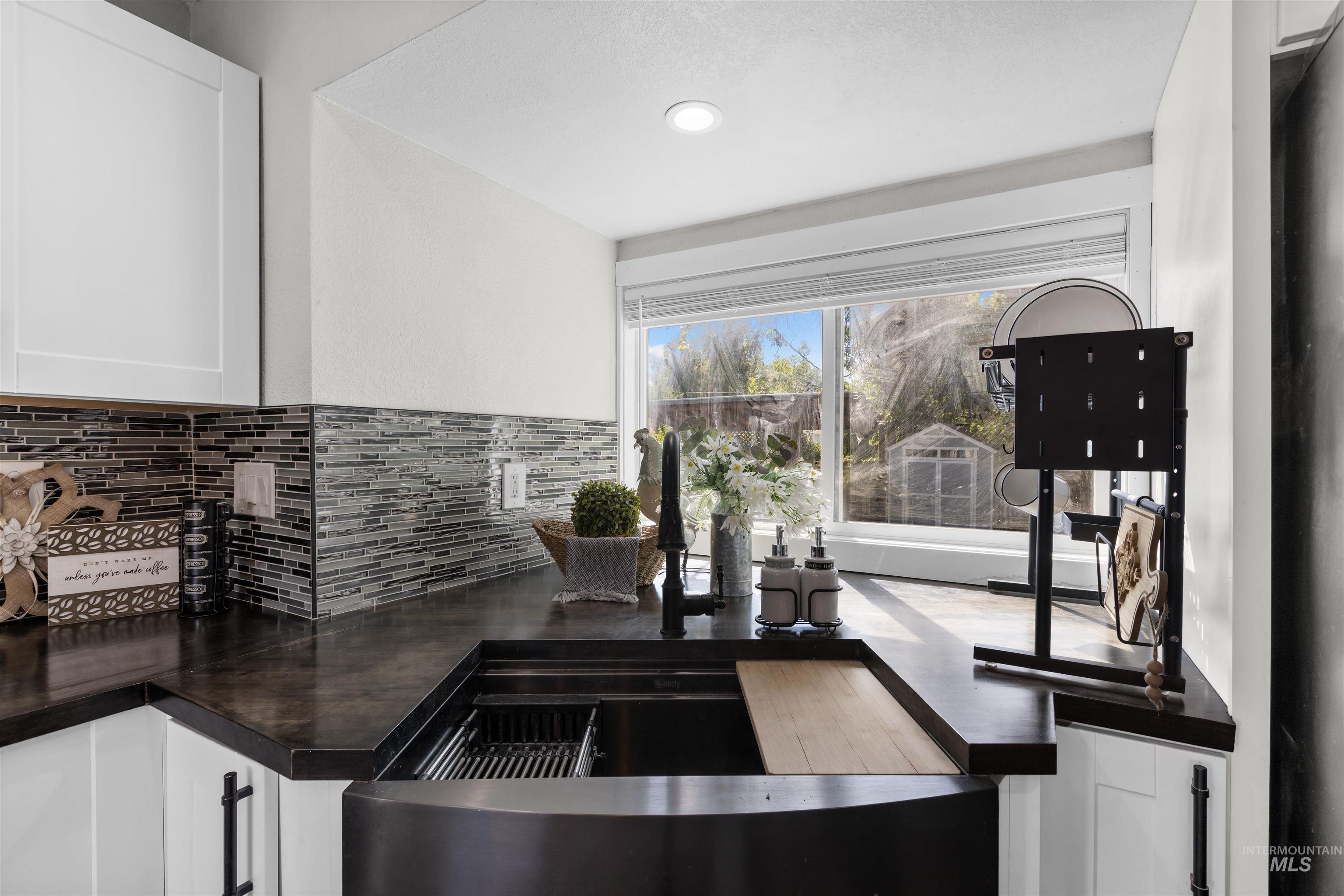 Kitchen workstation sink with built-in drying rack and cutting board beneath a sunny window.