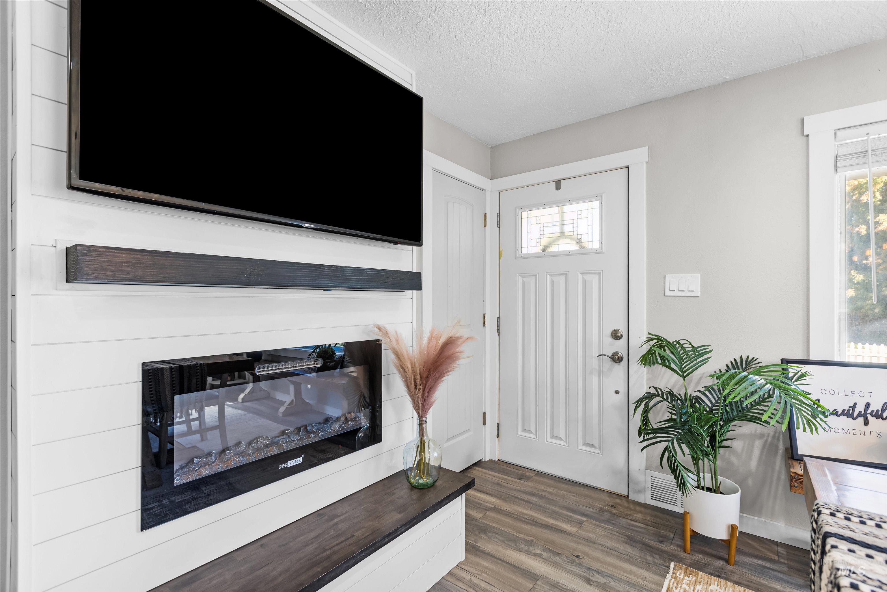 Furnished entryway with a glass-panel front door and shiplap media wall with television and fireplace.