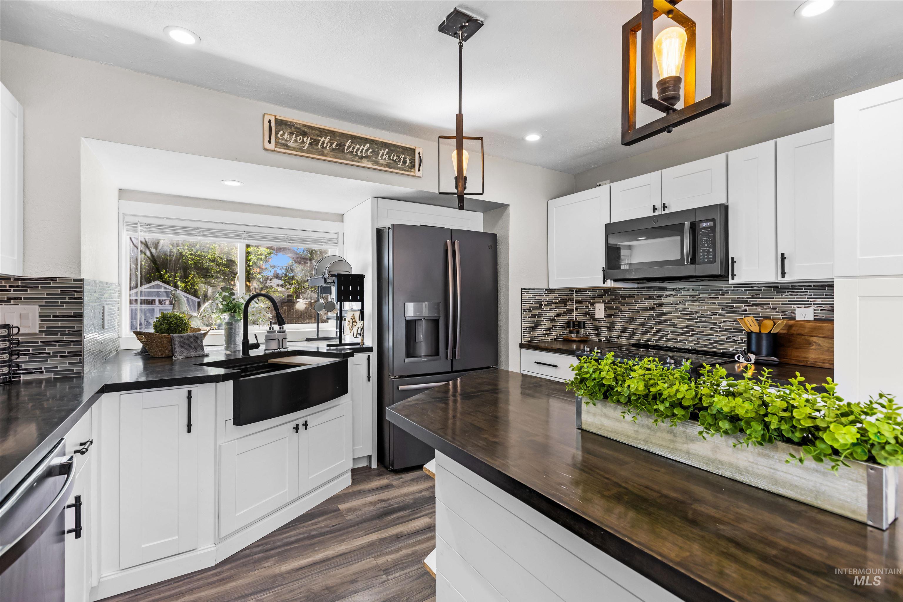 Bright kitchen with white cabinets, dark countertops, mosaic backsplash, and a large island.