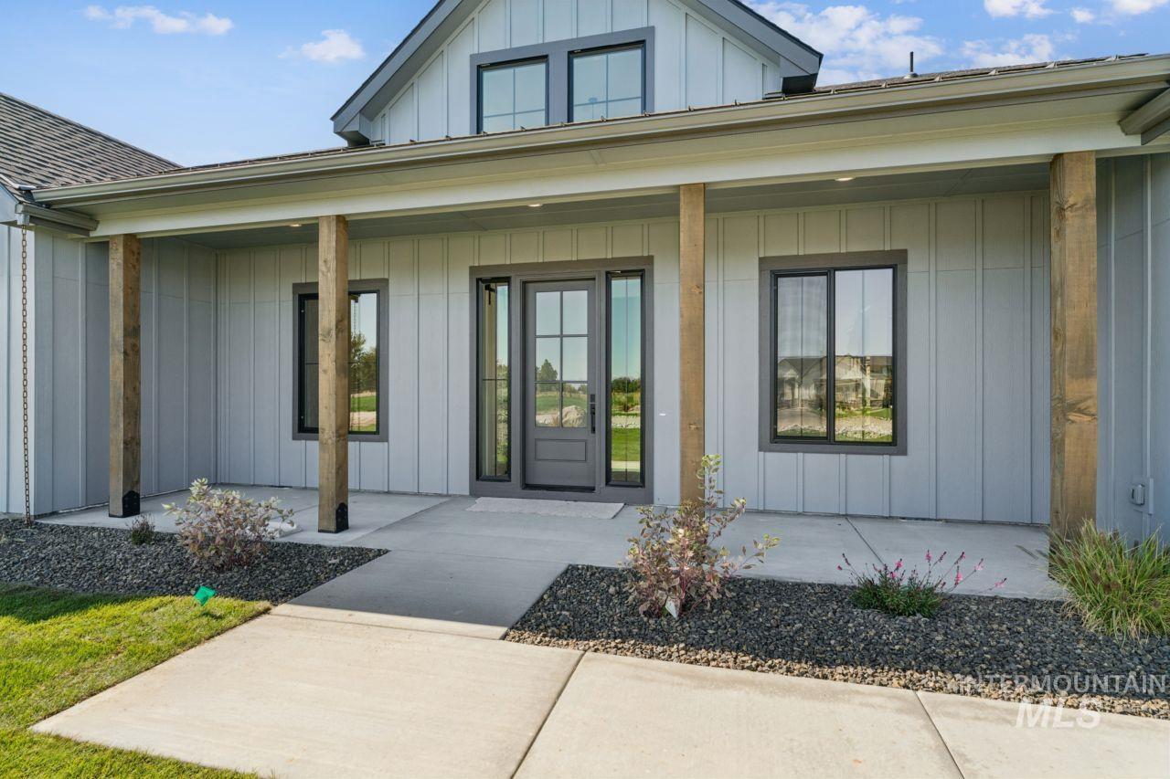 Gray two-story home with a deep covered porch, wood posts, and a concrete walkway.