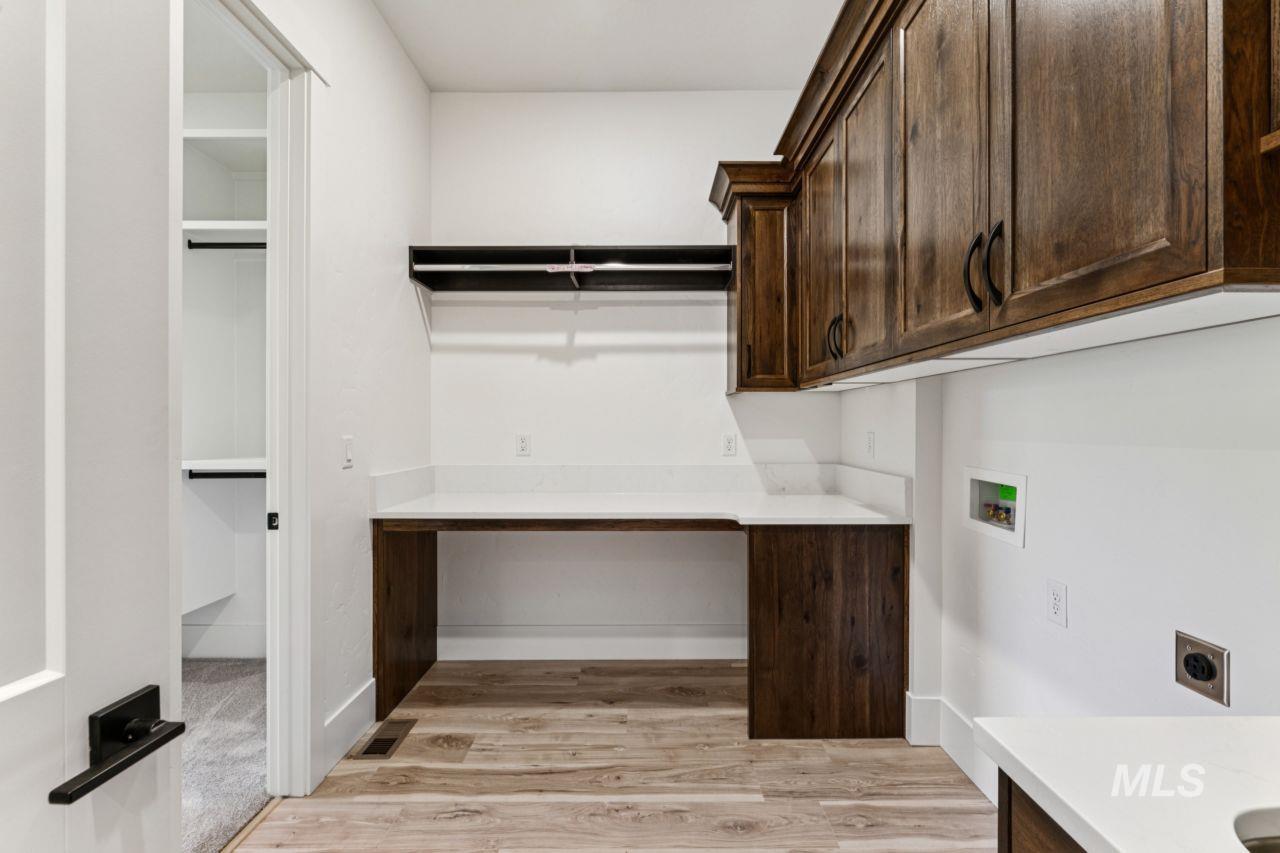 Laundry room with dark wood cabinets, white countertop, and washer and dryer hookups.