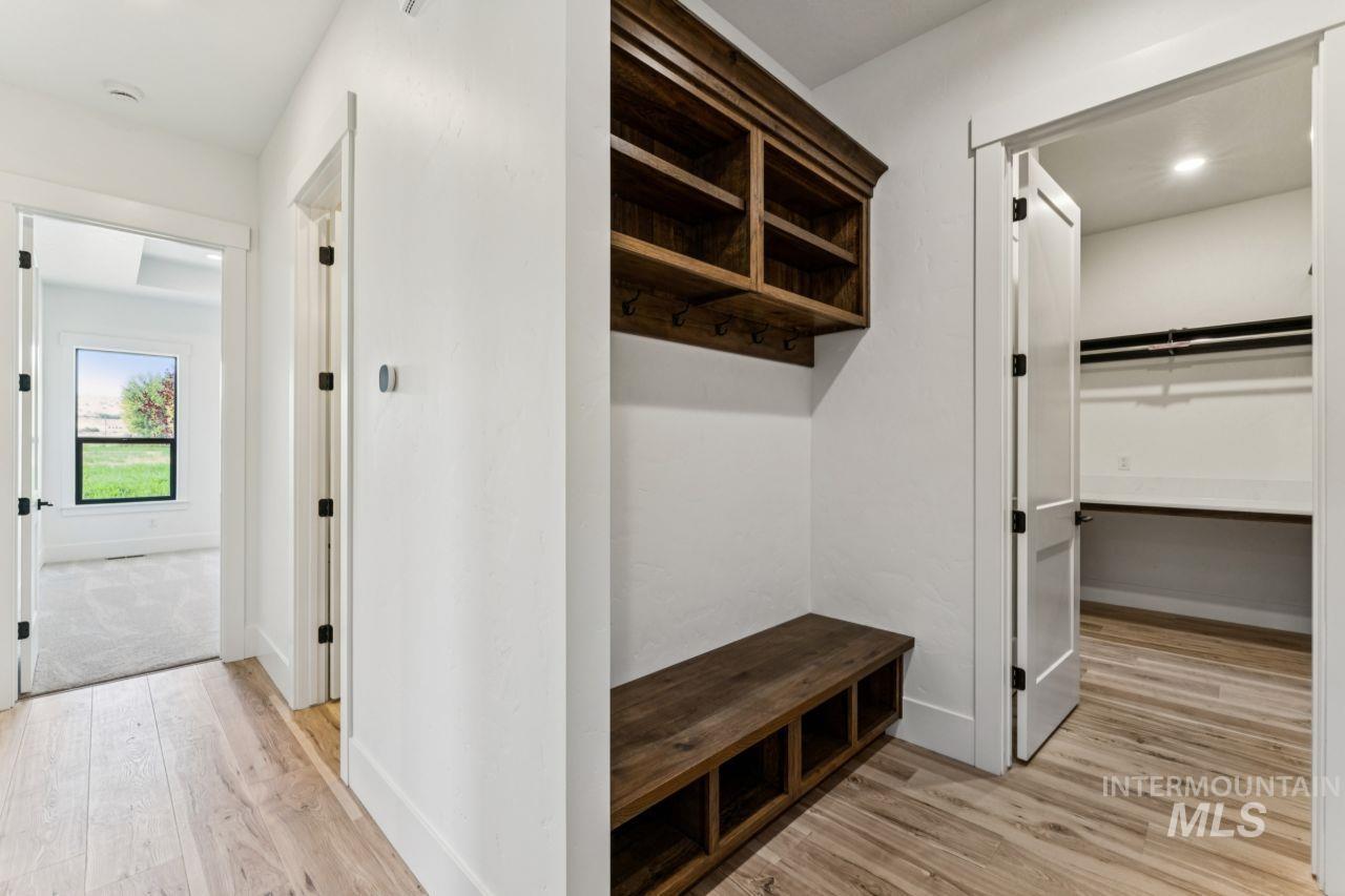 Mudroom with a dark wood built-in bench, cubbies and hooks beside an open walk-in closet.