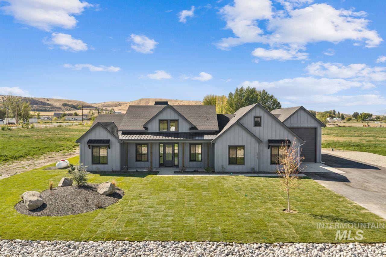 Gray modern farmhouse with multiple gables and an attached garage, set behind a landscaped lawn.