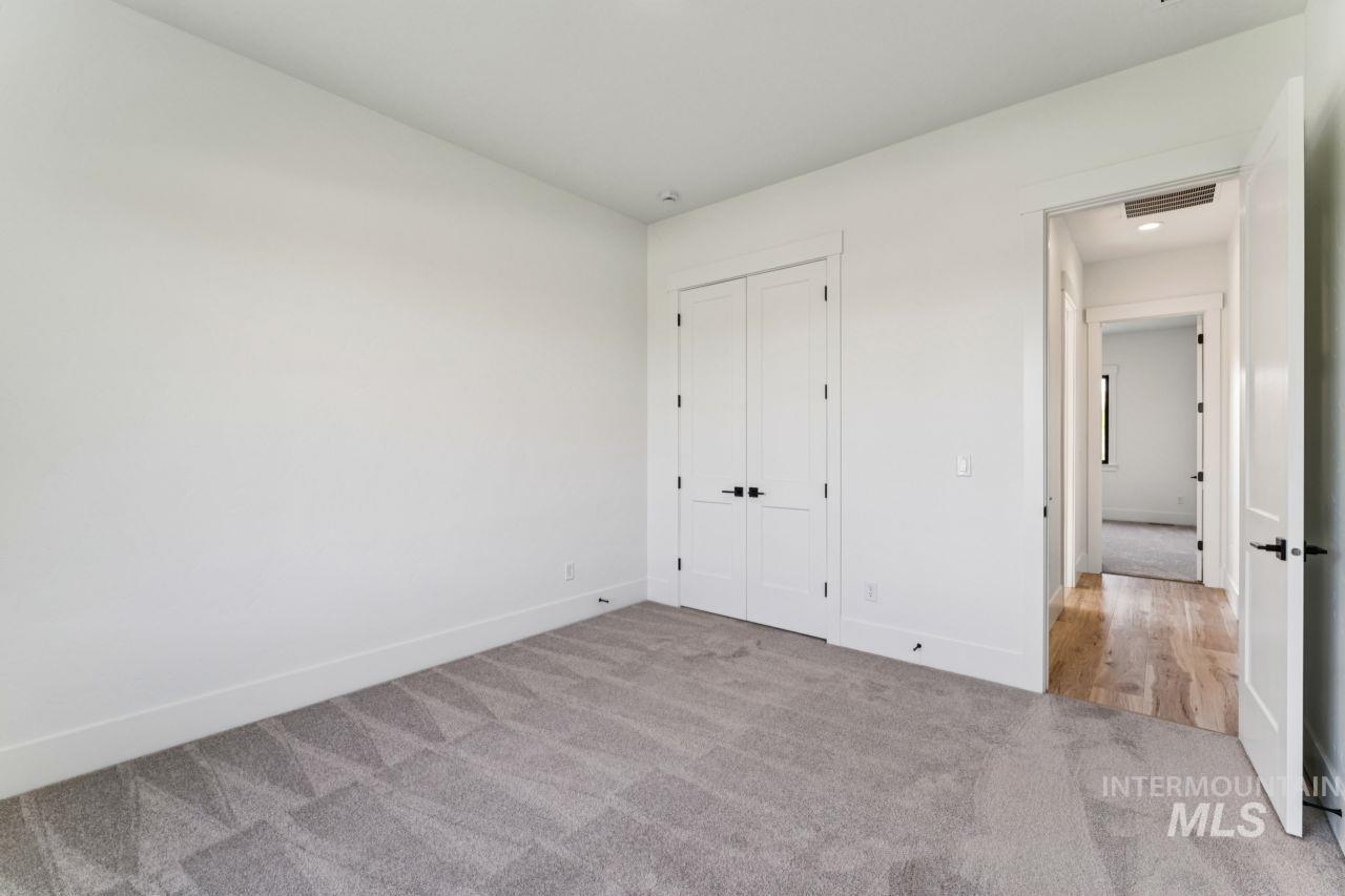 Empty bedroom with gray carpet, a double-door closet, and an open doorway to the hall.