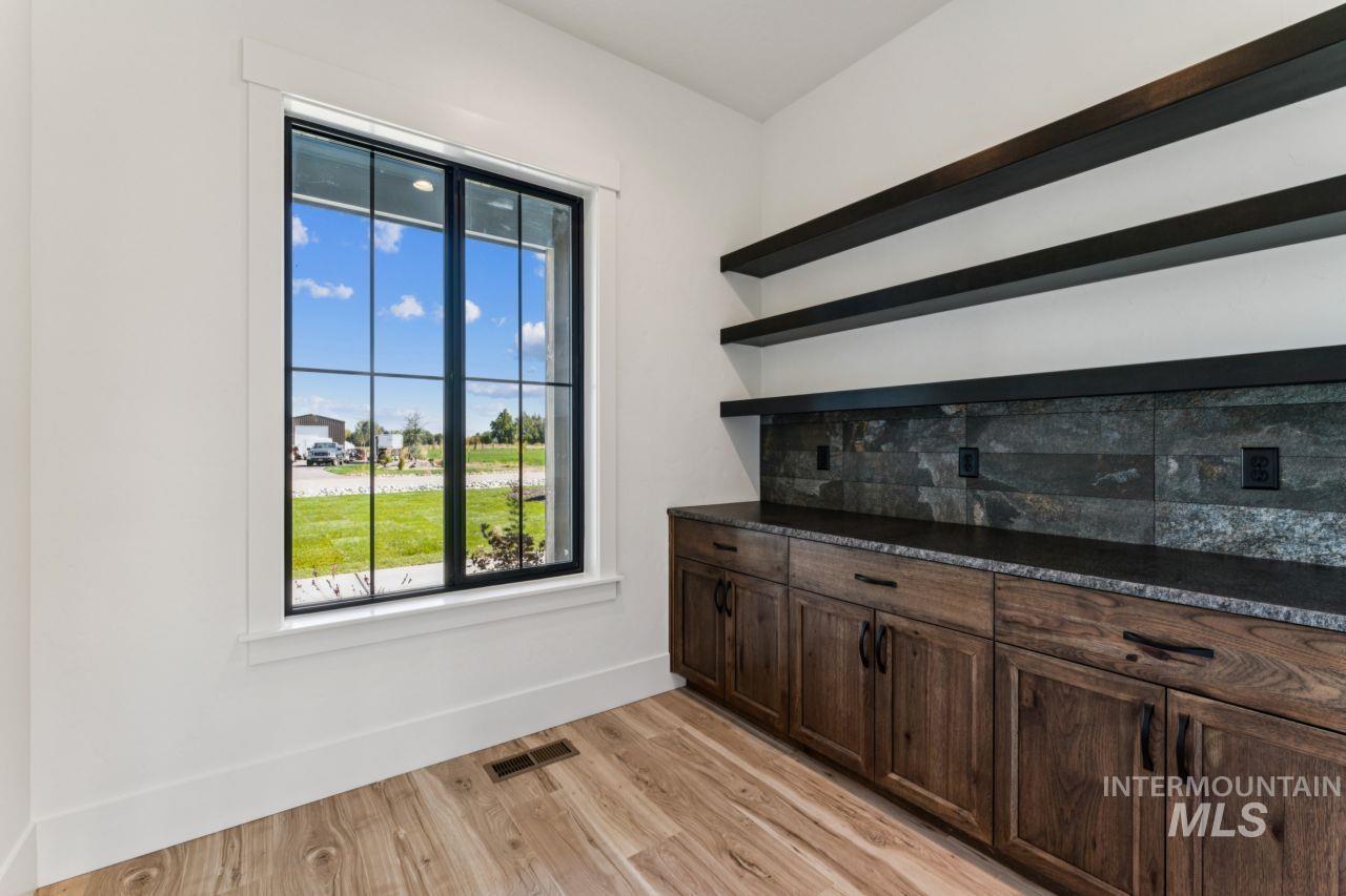 Built-in workspace with dark wood cabinetry and floating shelves beside a large window.
