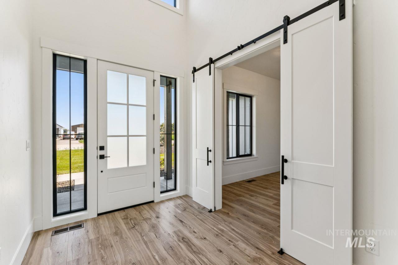 Entryway with a white front door, tall sidelights, wood-look floors, and sliding barn doors.