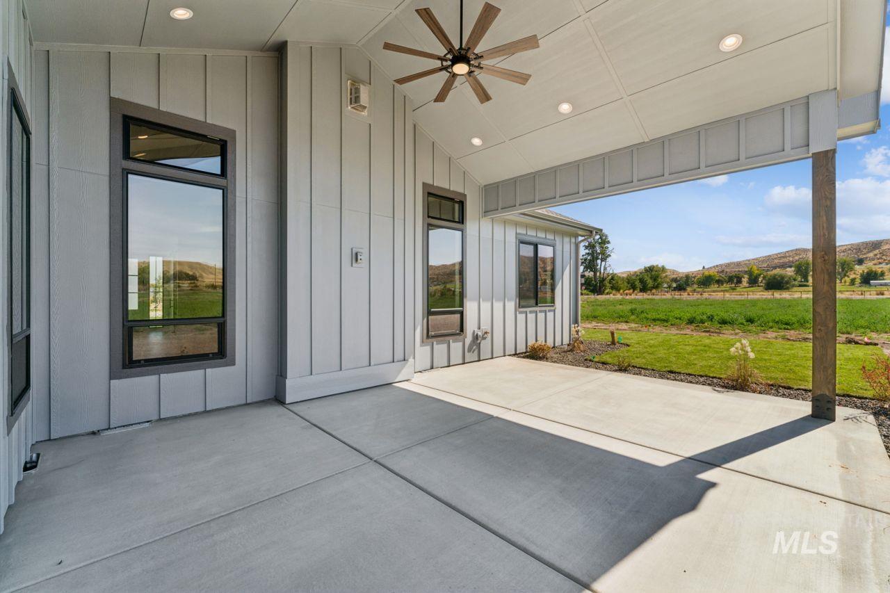 Covered concrete patio with a high ceiling and views across a lawn to rolling hills.