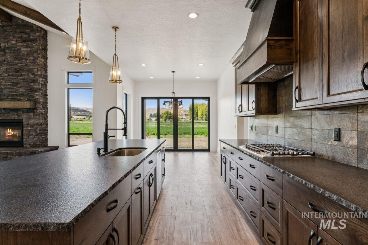 Modern kitchen with dark wood cabinetry, a large island, and sliding doors overlooking a green field.