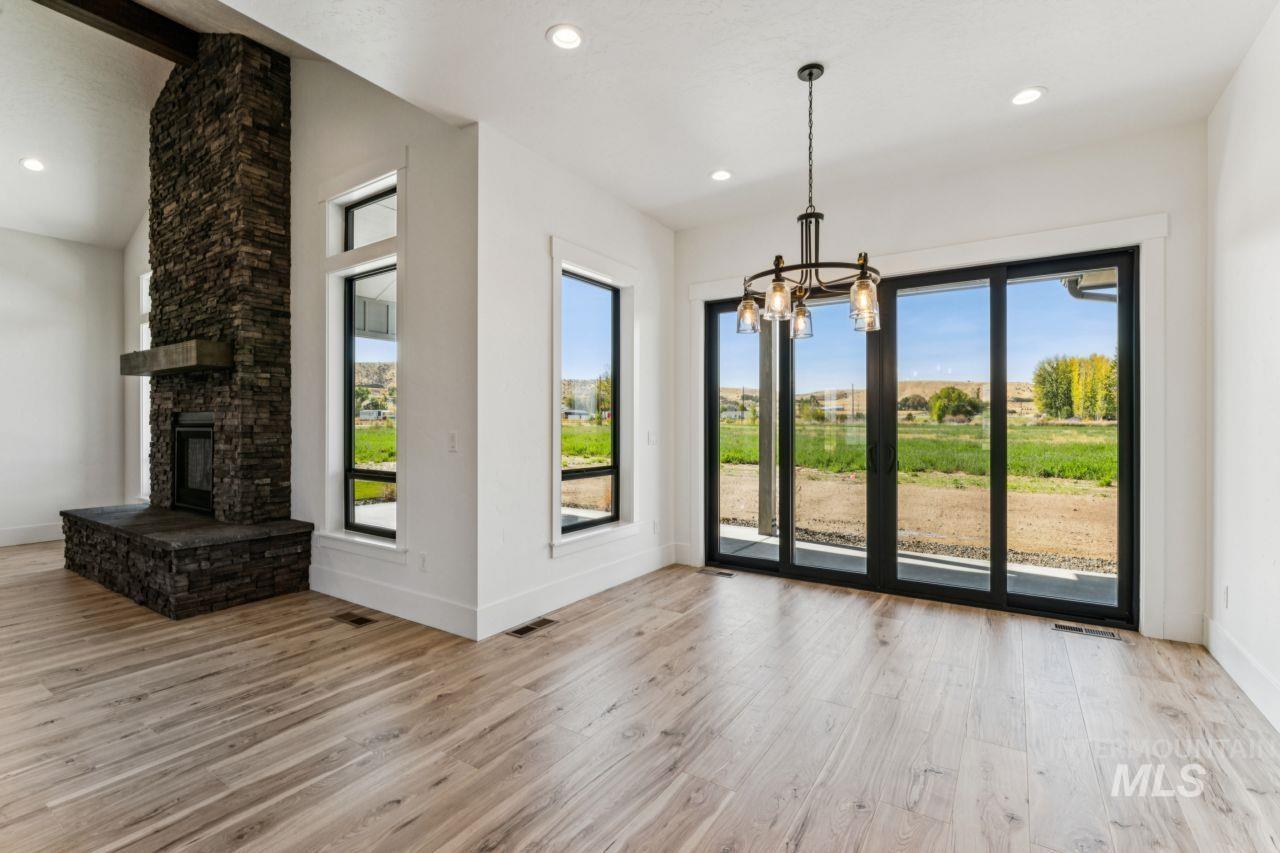 Vacant living room with a tall stone fireplace and sliding glass doors overlooking fields.