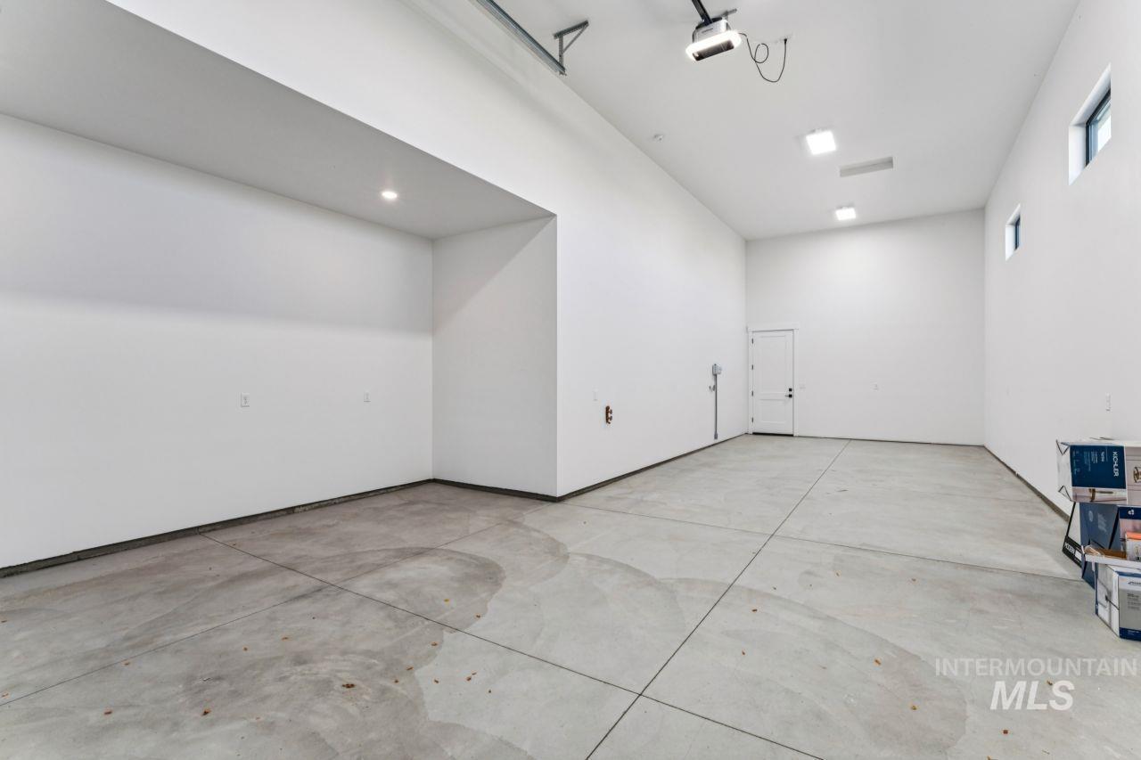 Spacious empty garage with a high ceiling, concrete floor, and small high windows.