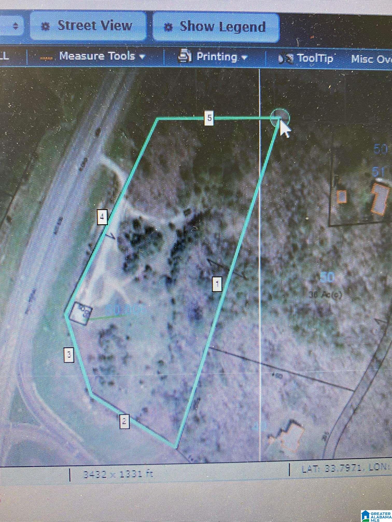 Aerial map of an irregular wooded parcel outlined in turquoise beside a road.