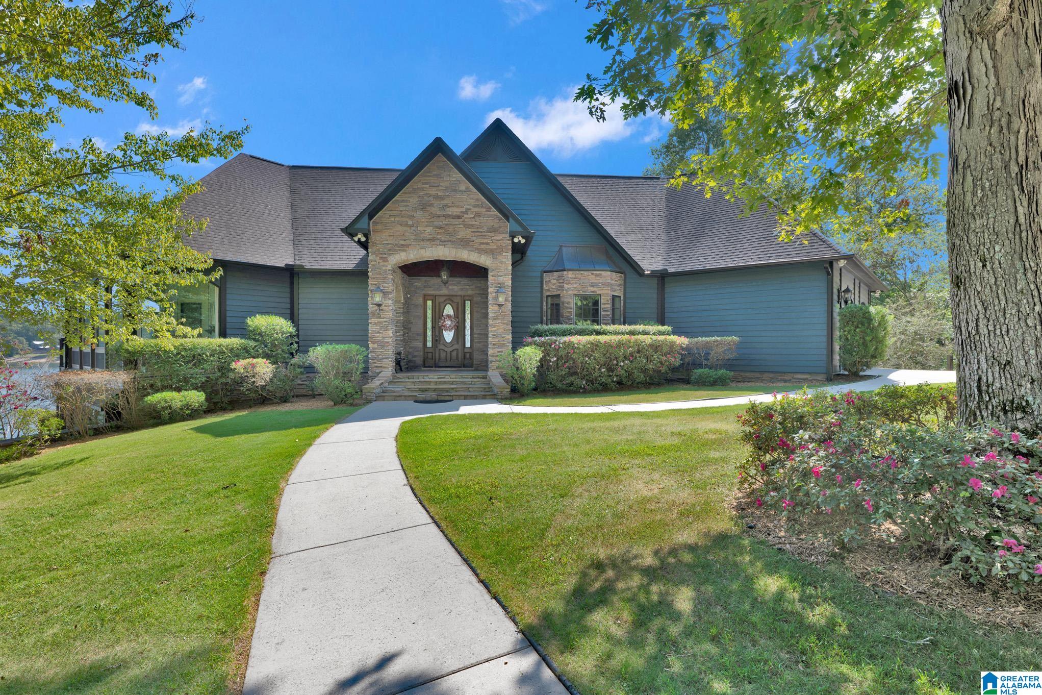 Blue-sided home with a stone entry, landscaped yard, and curved walkway.