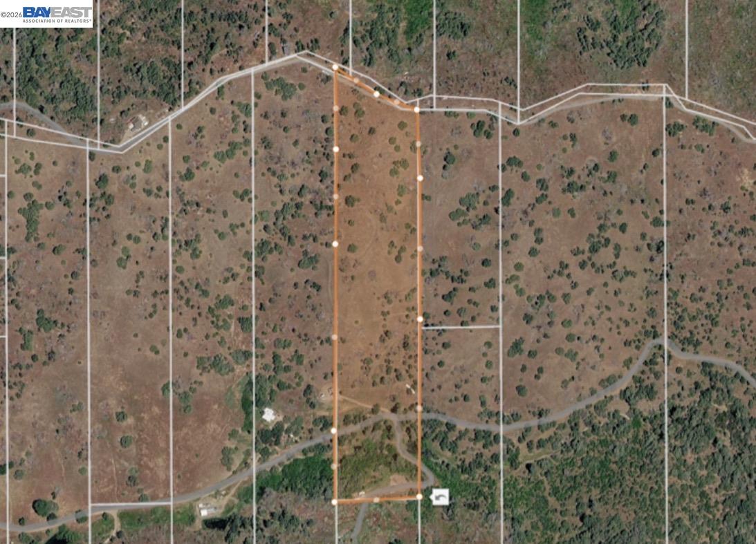 Rural parcel outlined in orange, with neighboring property lines and a road along its southern edge.