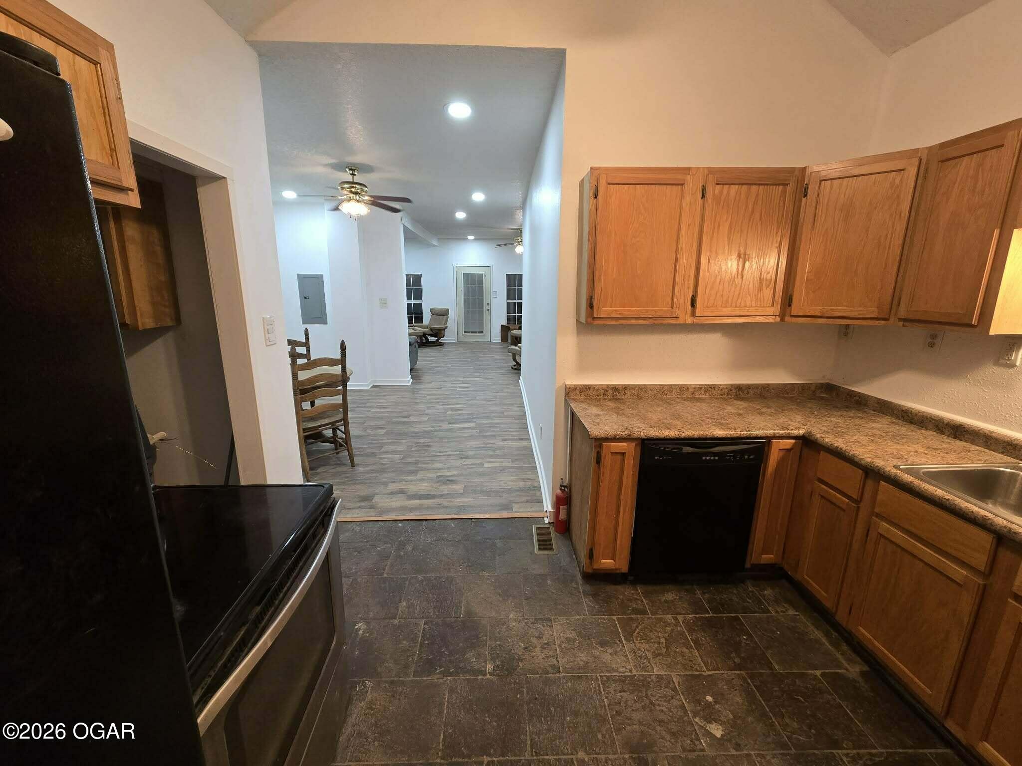 Kitchen with wood cabinets and brown countertops opening into a living area.