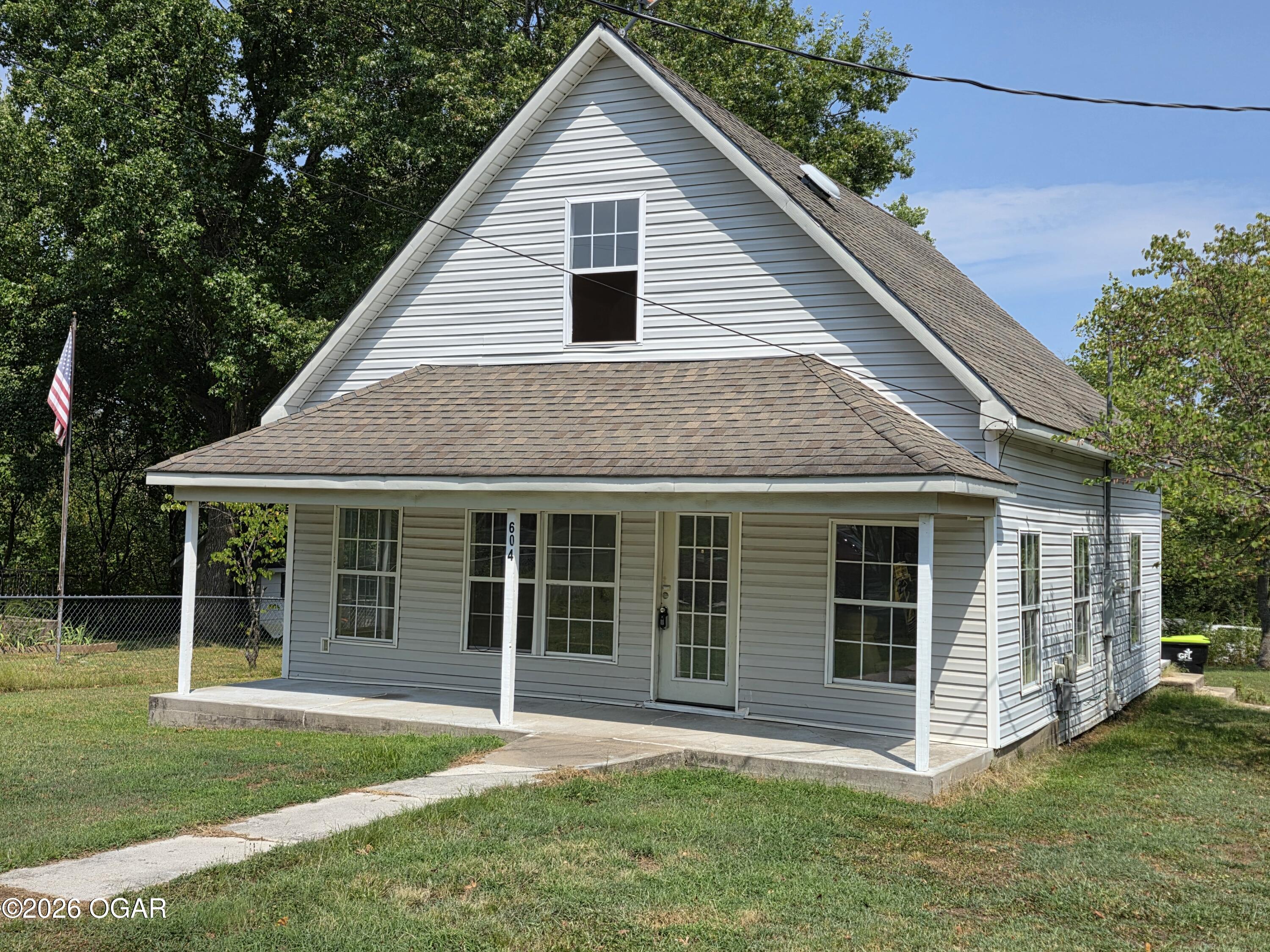 House with light gray siding, steep gable roof, and covered front porch.