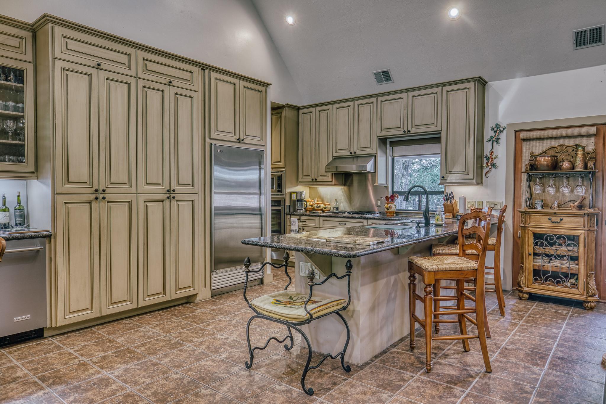 Kitchen with cream cabinets, stainless steel appliances, and a granite island with sink and seating.