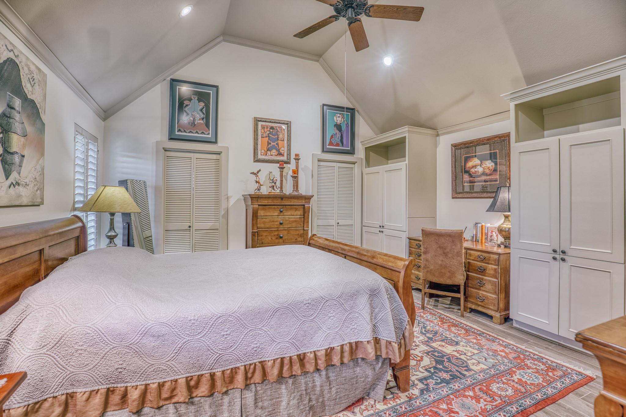 Furnished bedroom with a vaulted ceiling, built-in cabinets, and a large bed.