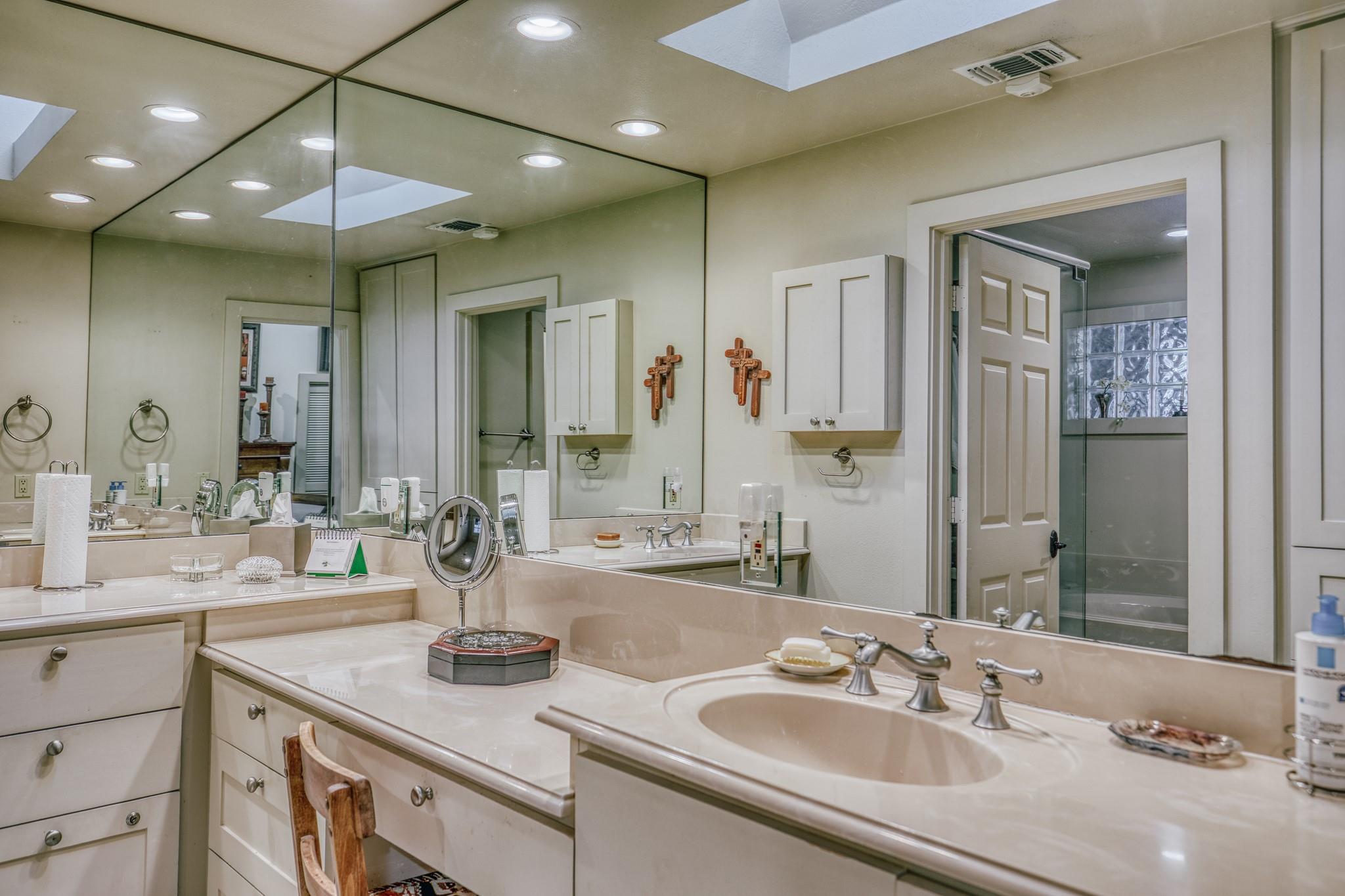 Bathroom with a long double vanity, expansive mirrors, and a glass-block shower window.