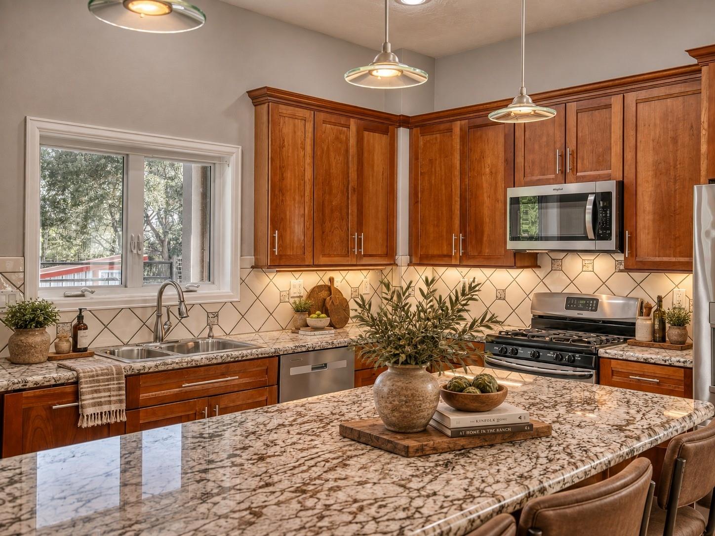 Kitchen with warm wood cabinets, a large veined stone island, and stainless steel appliances.