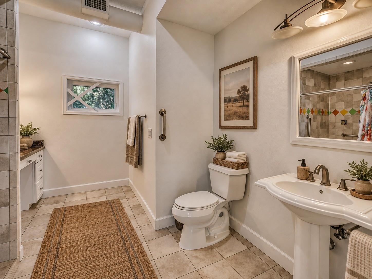 Bathroom with pedestal sink, toilet, and mirrored view of a tiled walk-in shower.