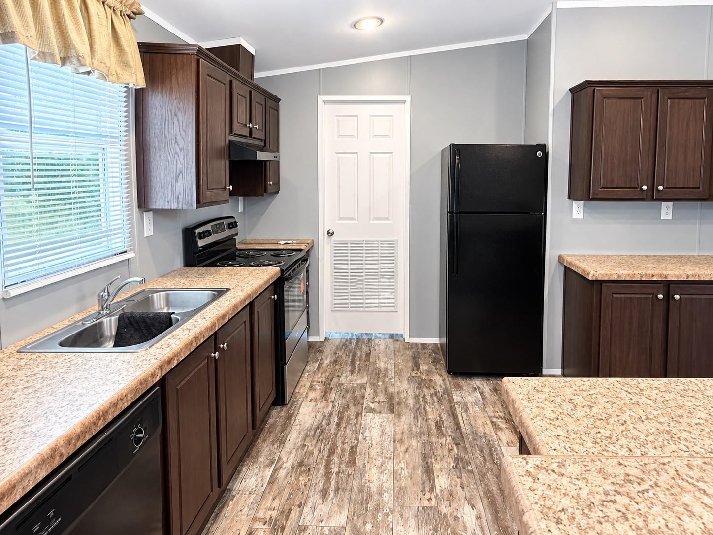 Kitchen with dark wood cabinets, patterned countertops, and a double-basin sink beneath a window.
