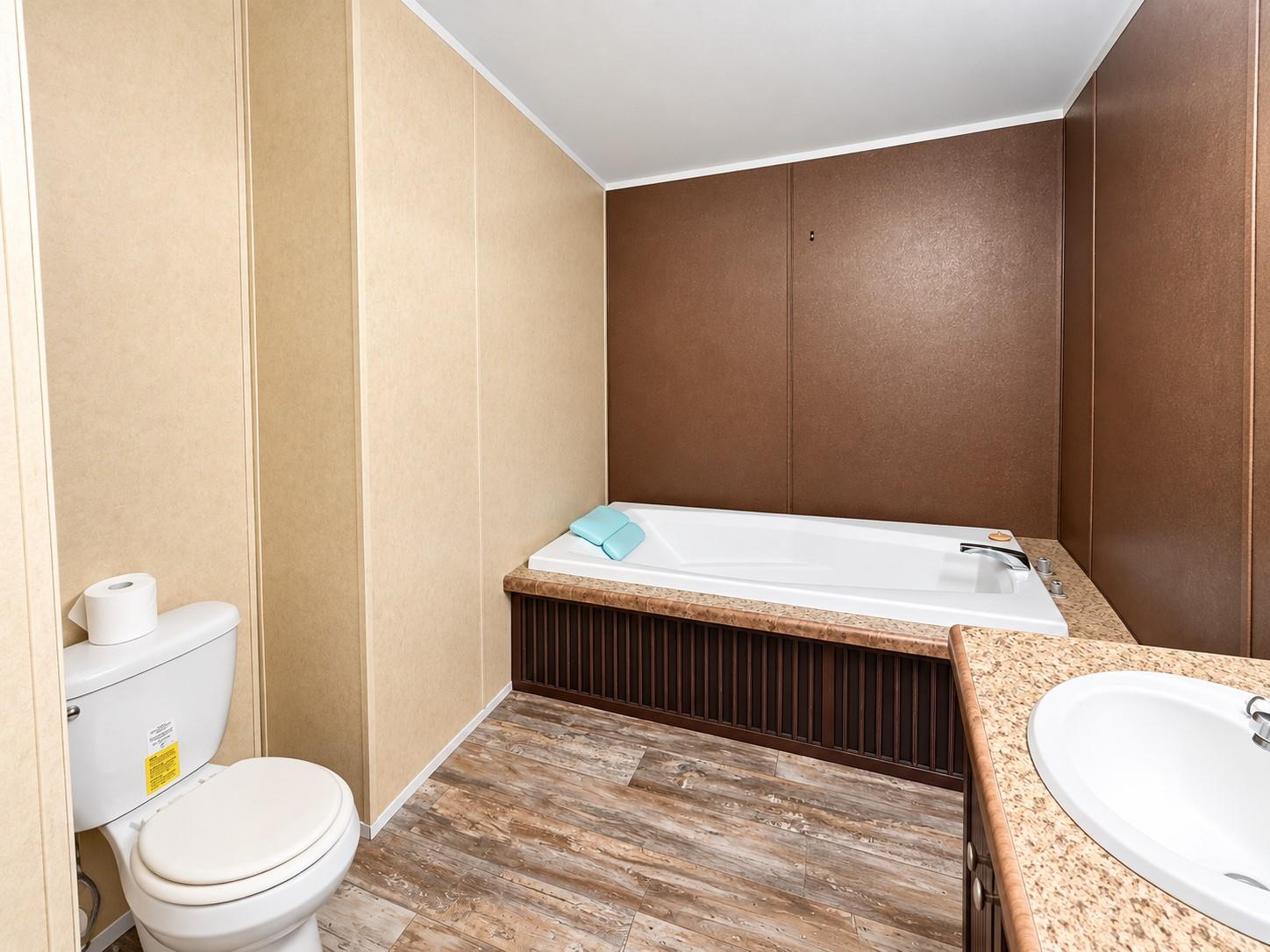 Bathroom with a built-in soaking tub, toilet, and granite-look vanity.