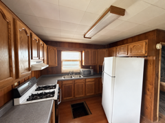 Kitchen with dark wood cabinets, a gas range, white refrigerator, and small window.