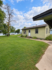 Single-story pale yellow house beside a mowed lawn and curving concrete walkway.