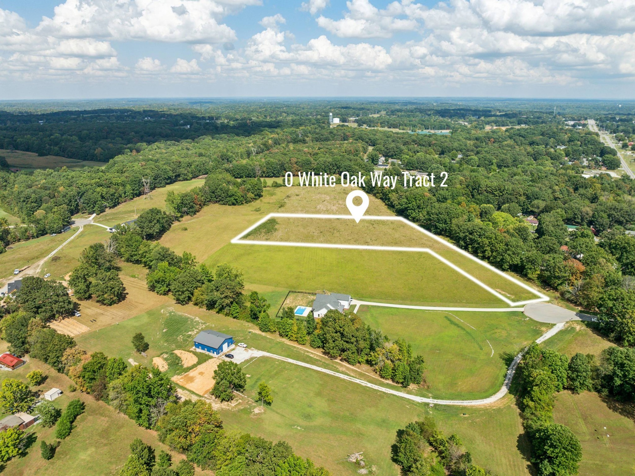 Aerial view of an outlined vacant tract surrounded by fields and wooded land.