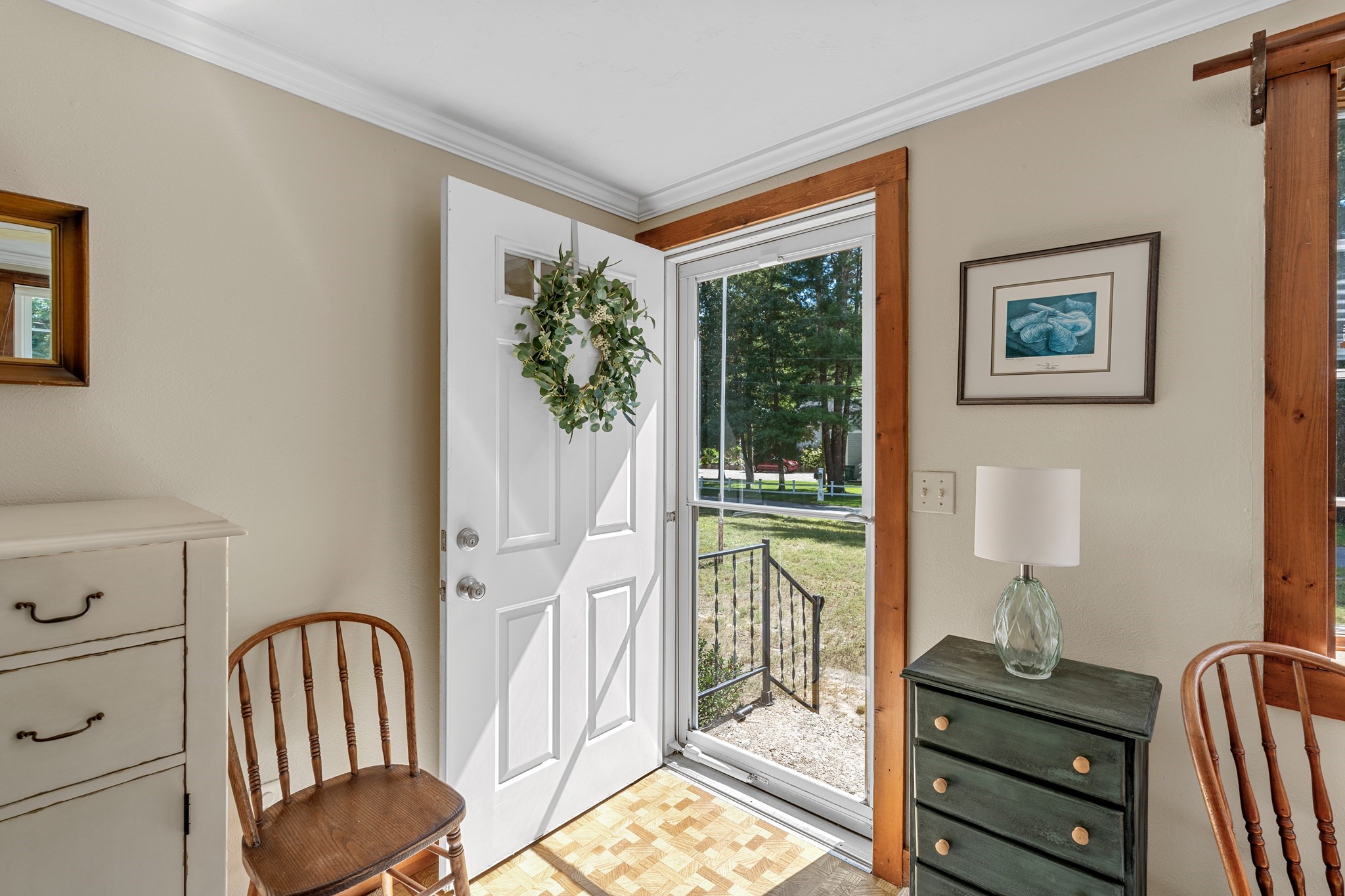 Furnished entry with an open white front door, natural wood trim, and a wreath.