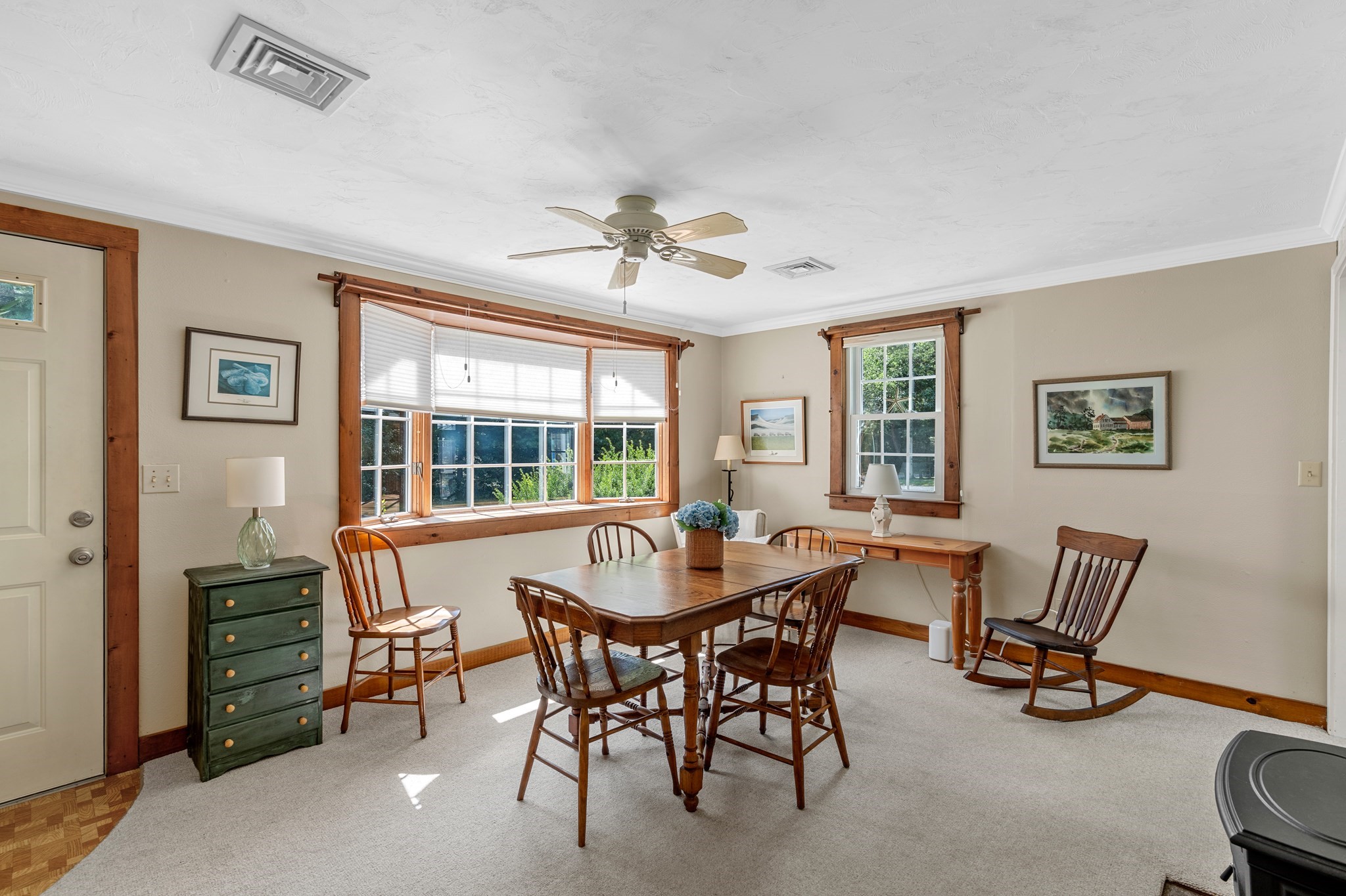 Dining room with a wooden table, chairs, and broad wood-trimmed windows.