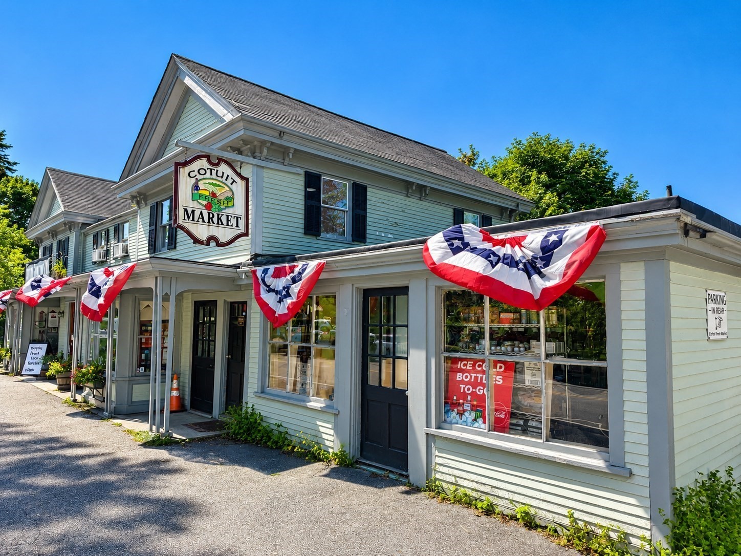 Cotuit Fresh Market storefront with a prominent hanging sign and patriotic bunting.