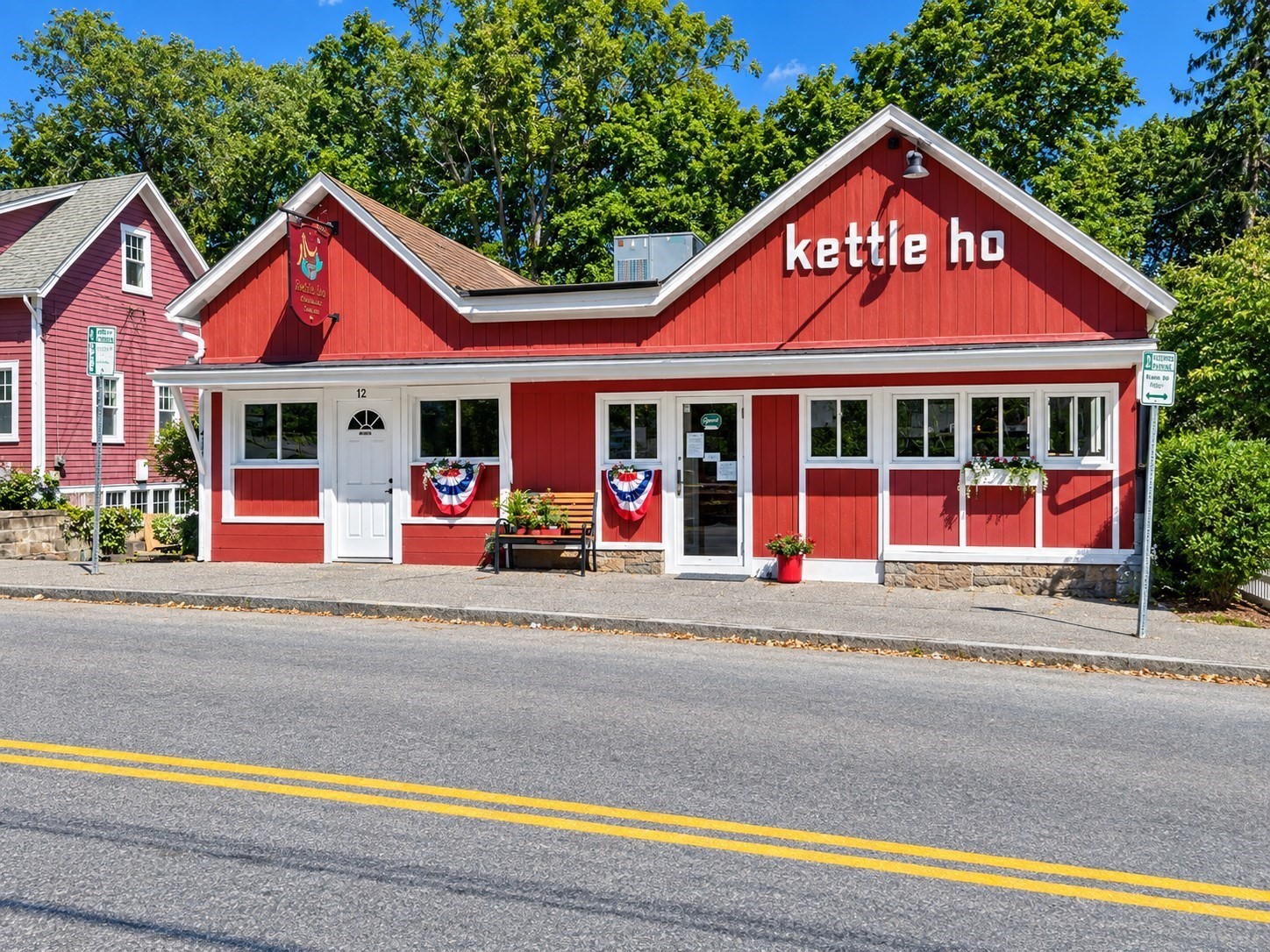 Red storefront with white trim, a stepped gabled roof, and patriotic bunting.